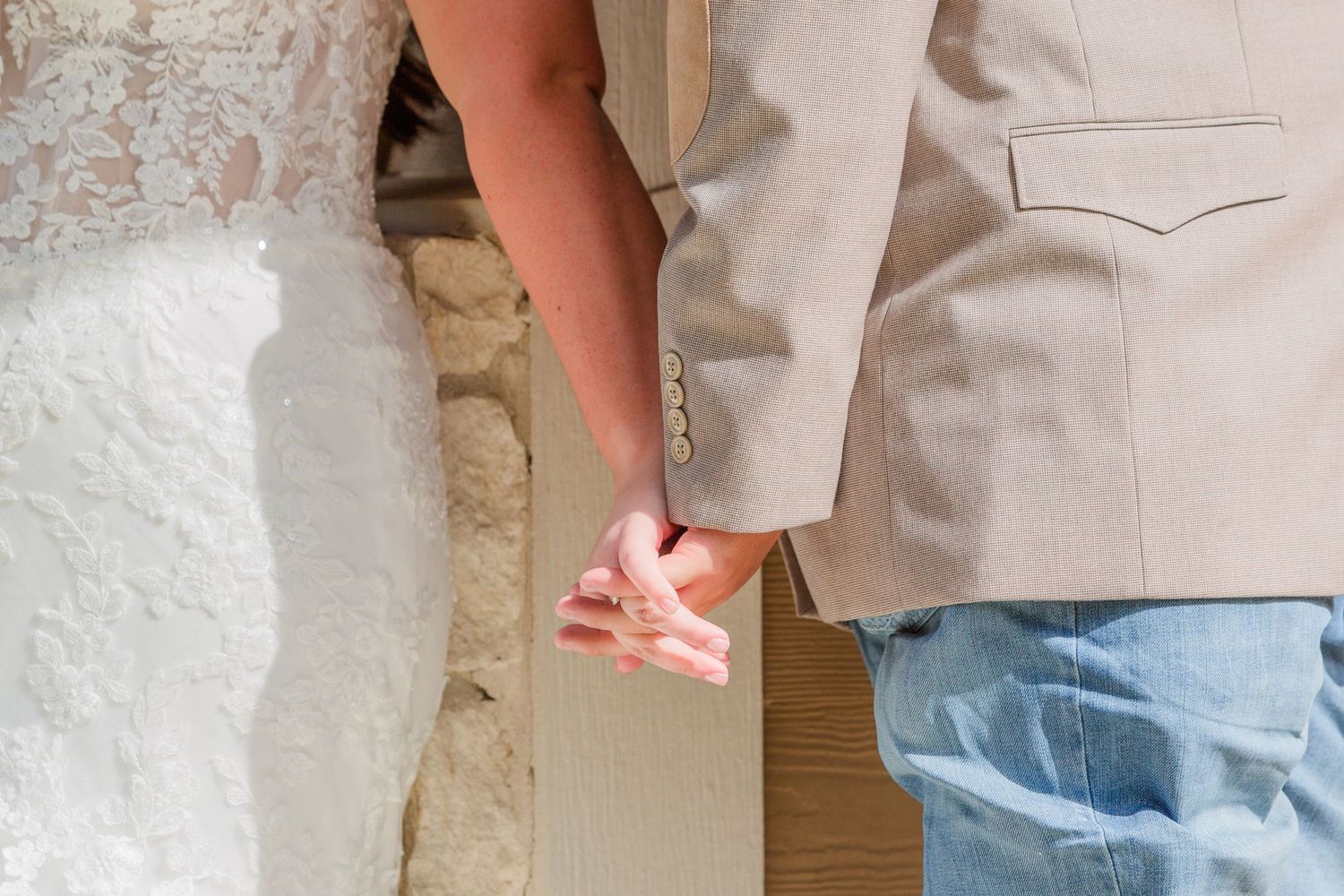 Close-up details of light colored wedding attire and blue jeans.