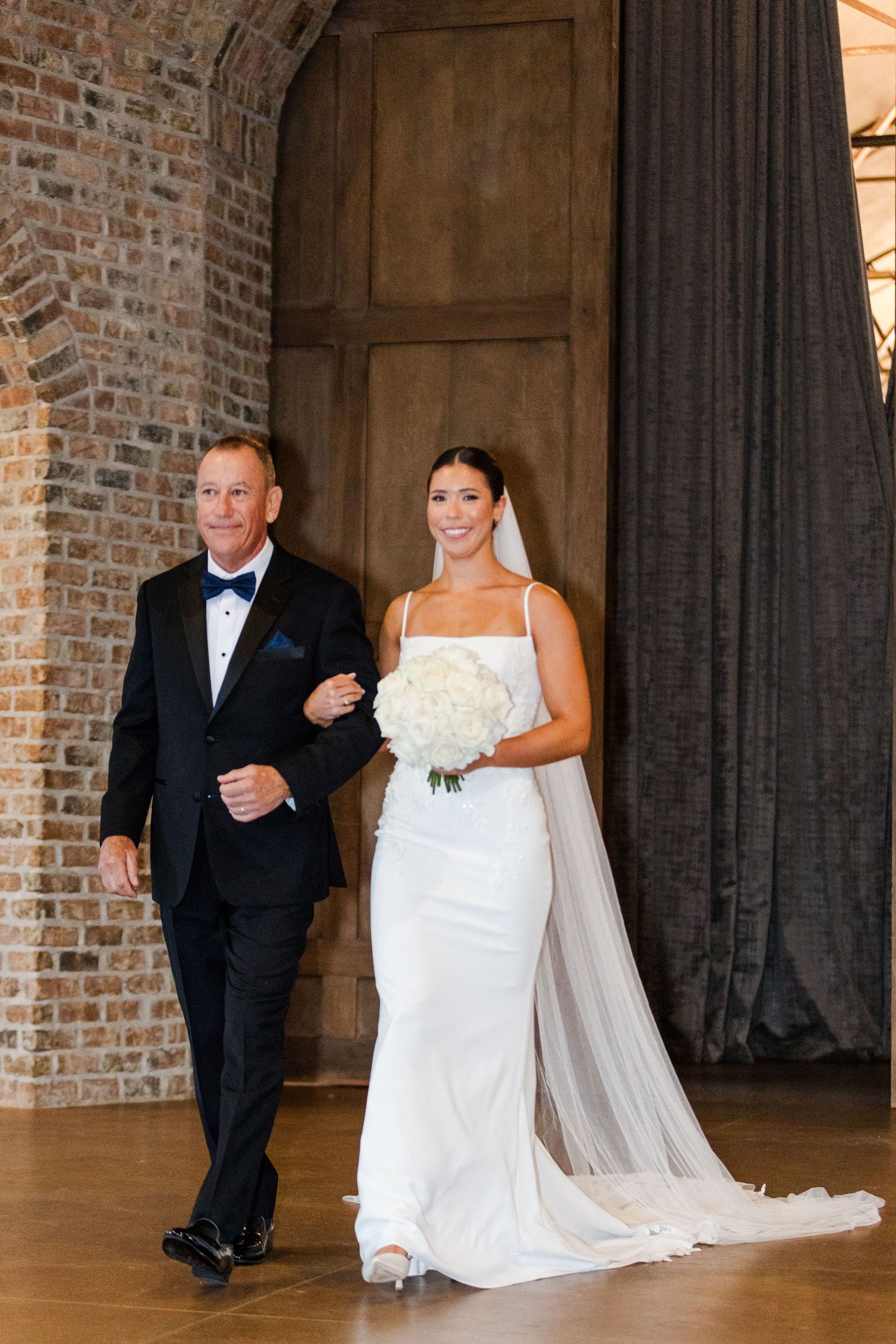 Wedding processional moment captured in an industrial brick and wood venue space.