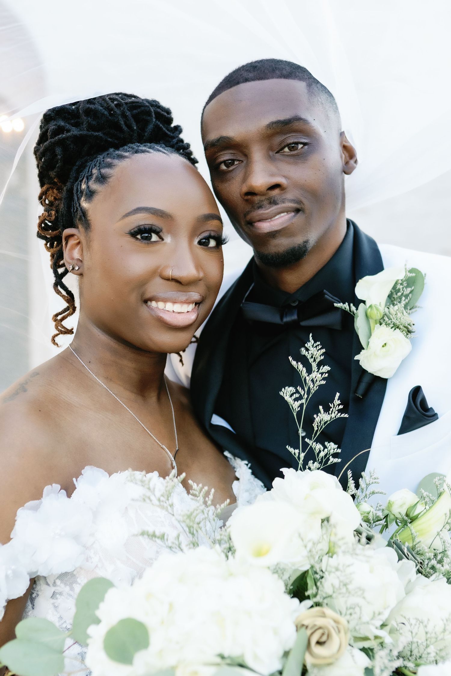 Joyful newlyweds embrace and share tender moments during their wedding photoshoot with white florals.