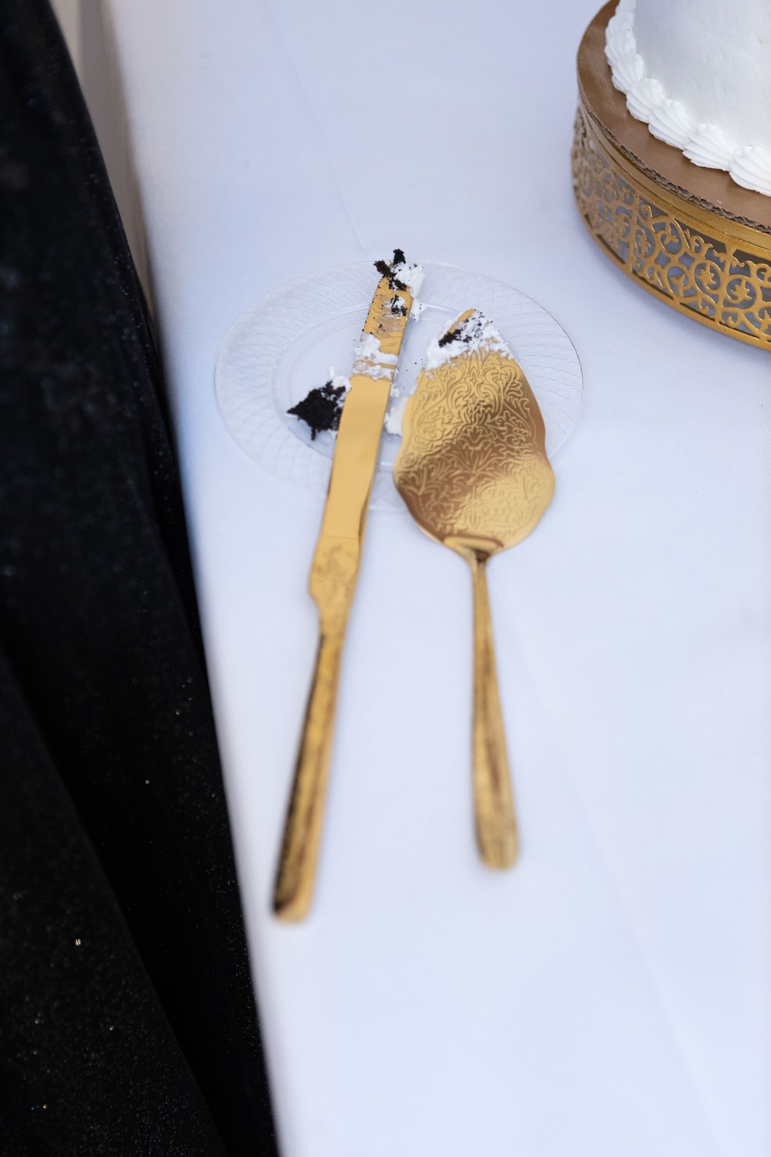 Golden utensils with cake remnants lying on a white surface.