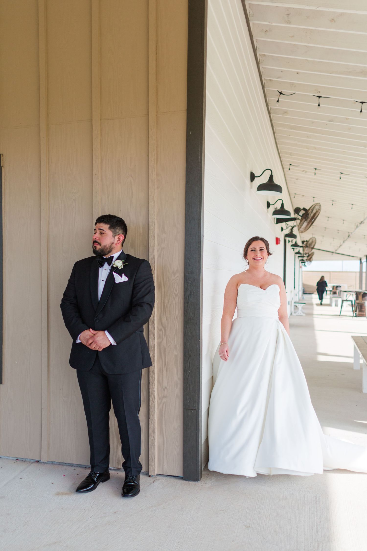 Wedding couple stands separated by wall during emotional first look photograph.