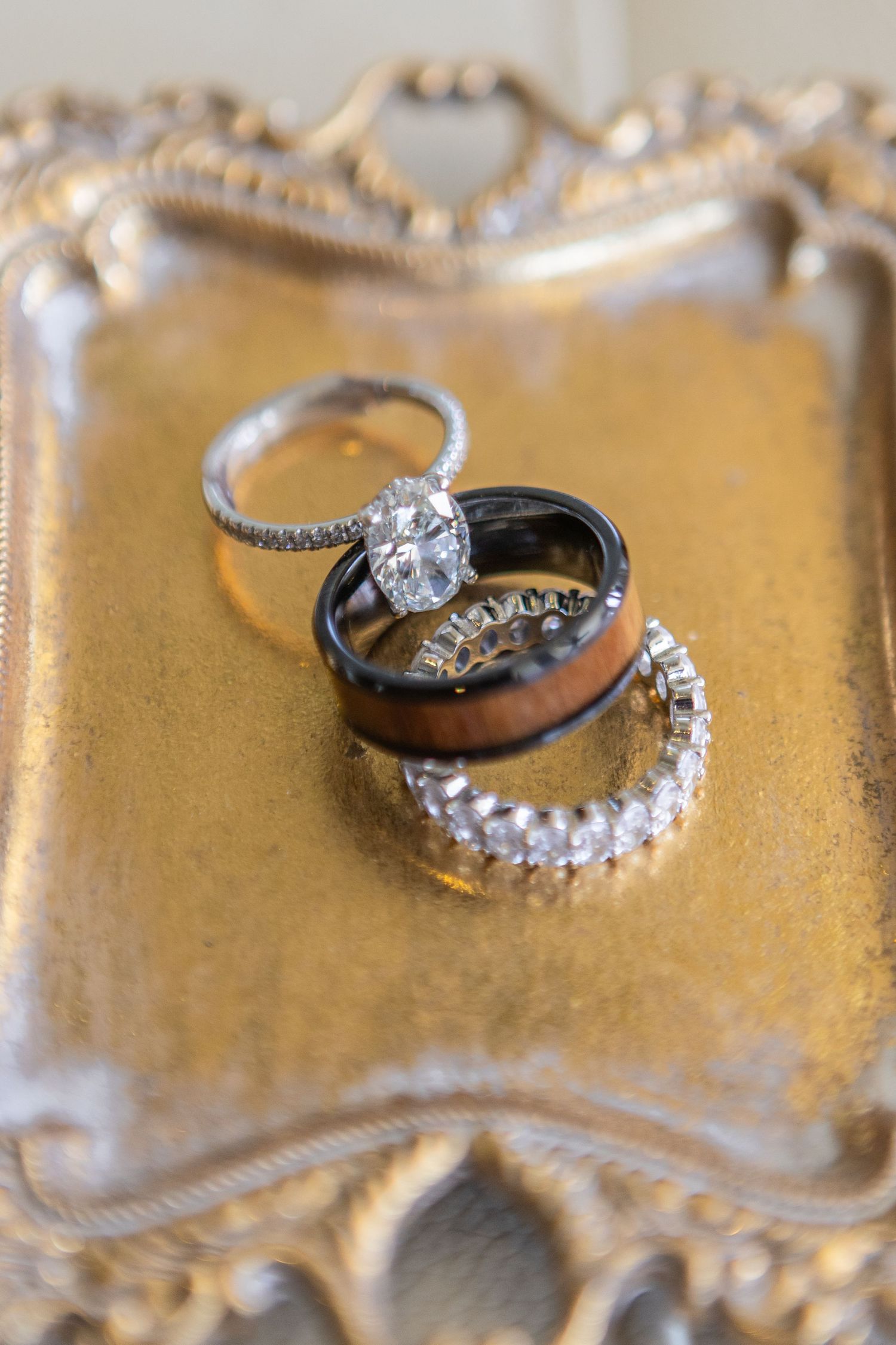 Diamond wedding rings and engagement bands arranged on ornate gold tray.