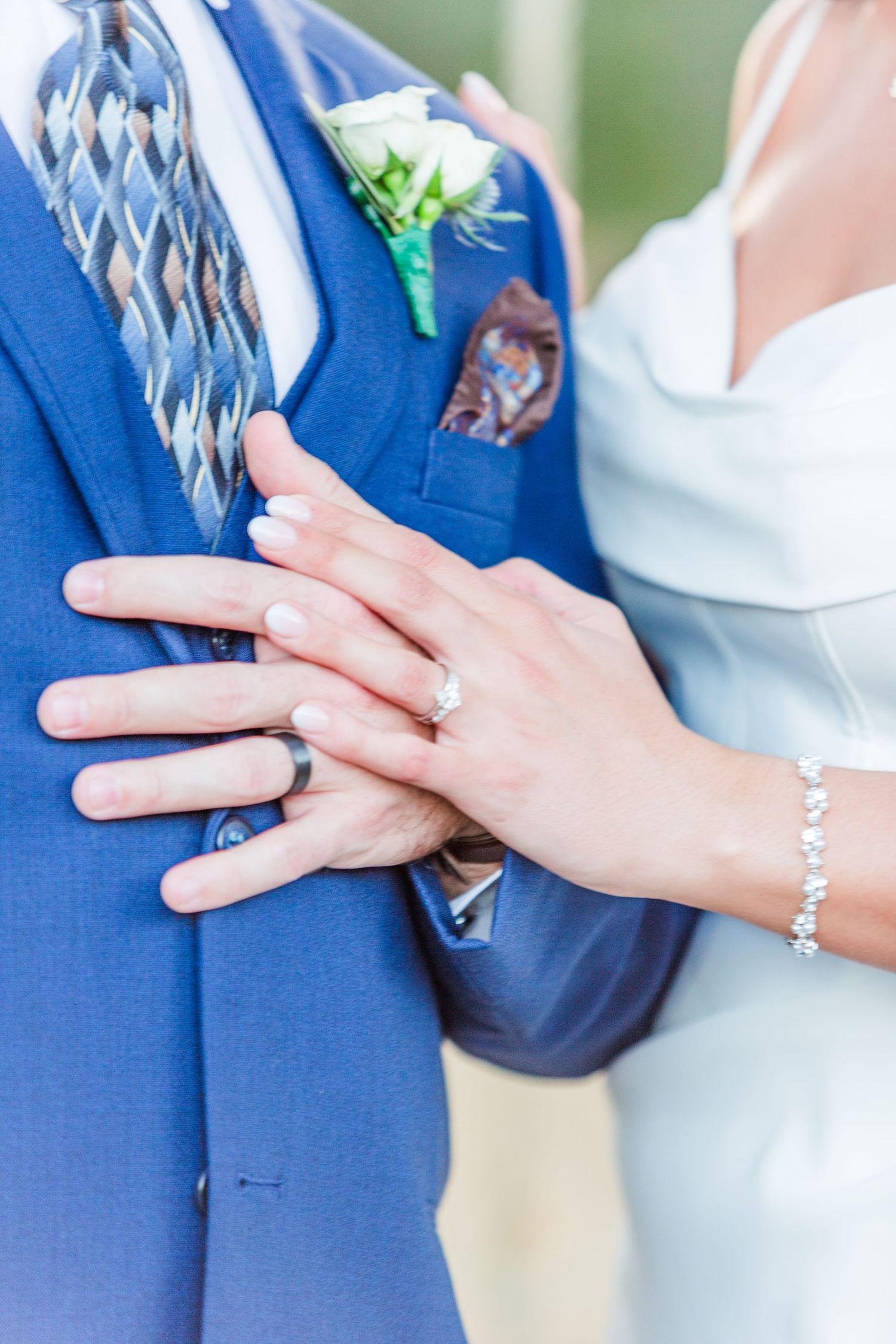 Close-up of wedding rings and hands during an outdoor ceremony.