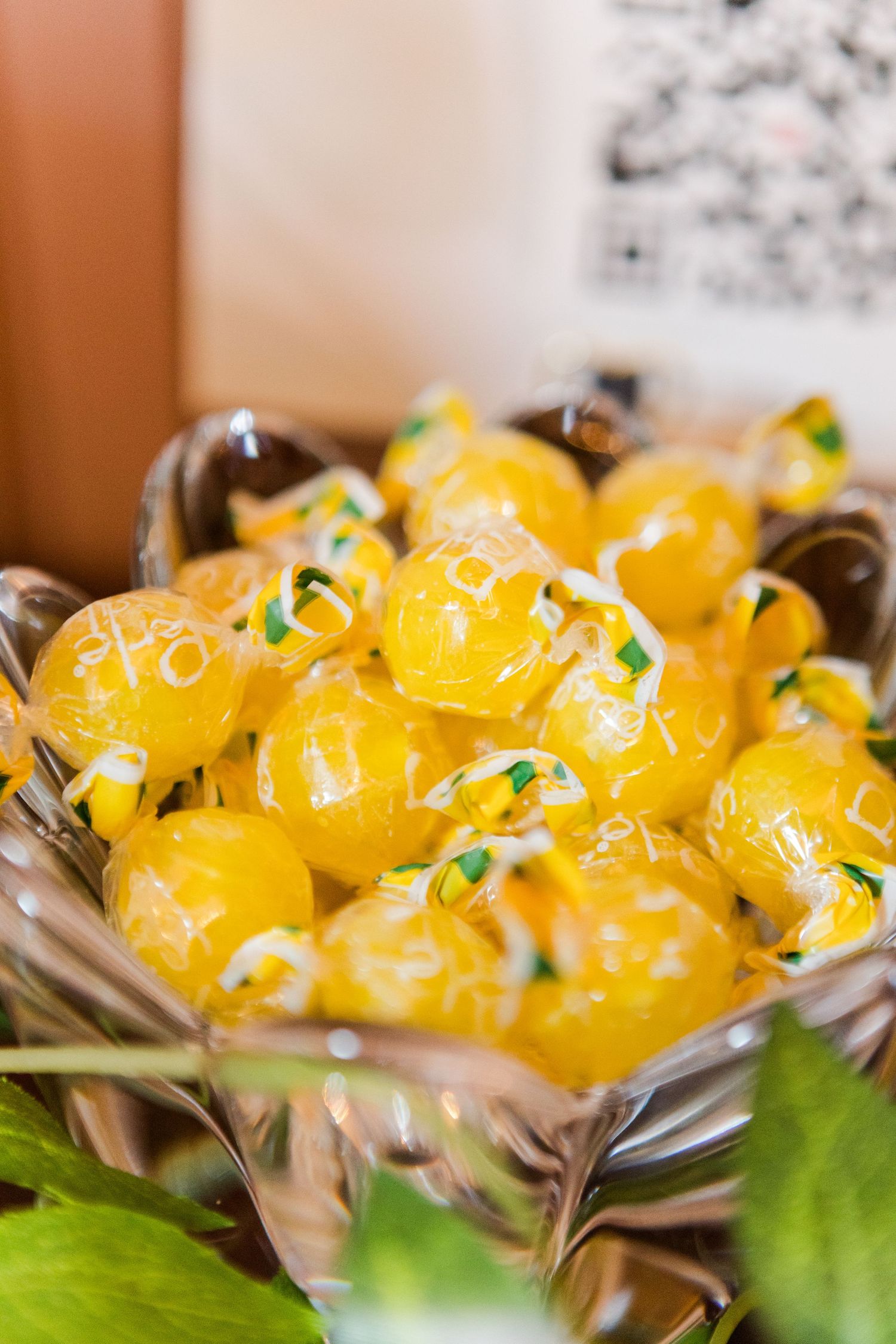 Yellow dessert bites decorated with green garnish displayed in silver serving dishes.