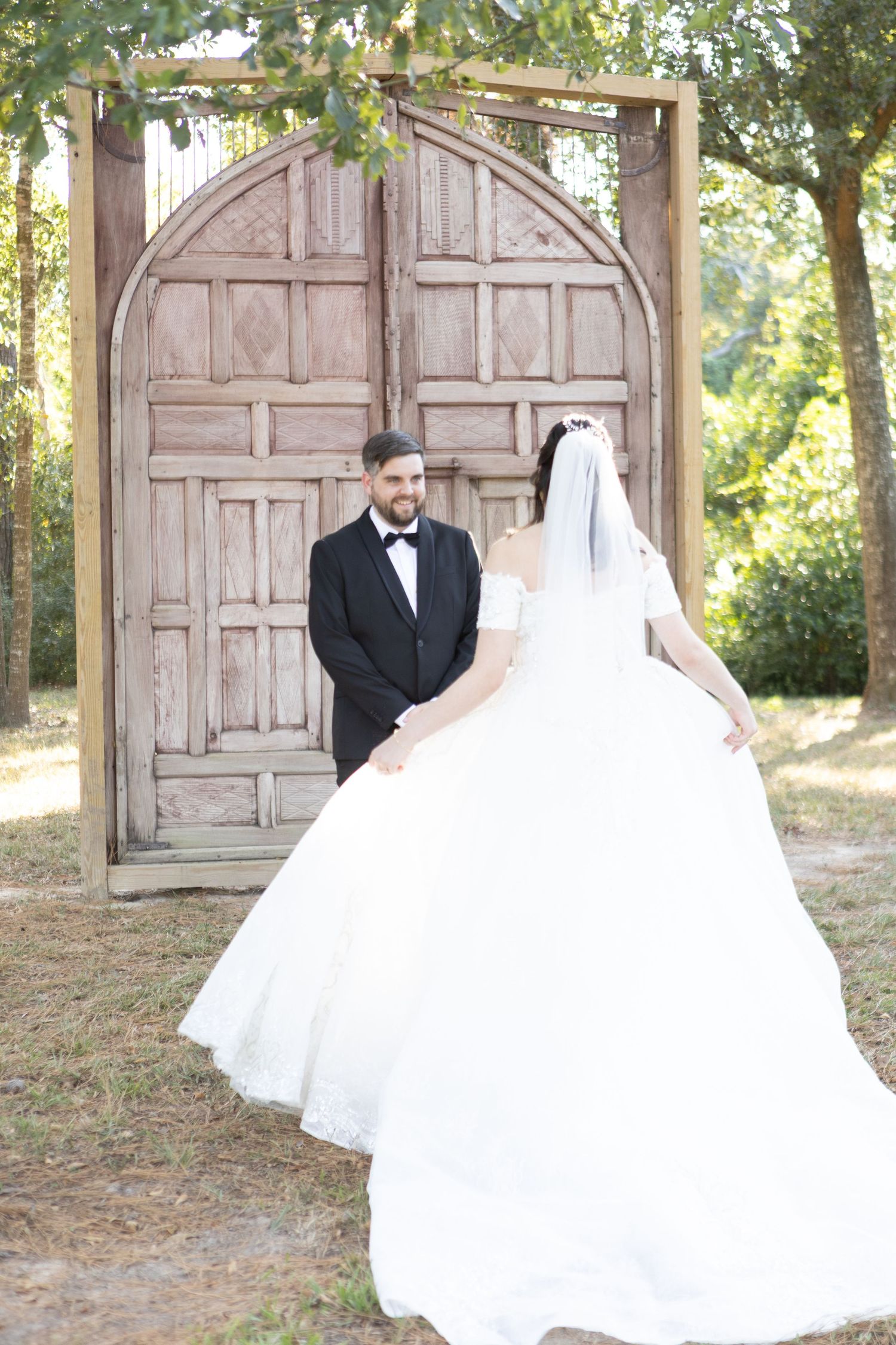 Romantic wedding portrait in front of vintage arched doors with natural lighting.