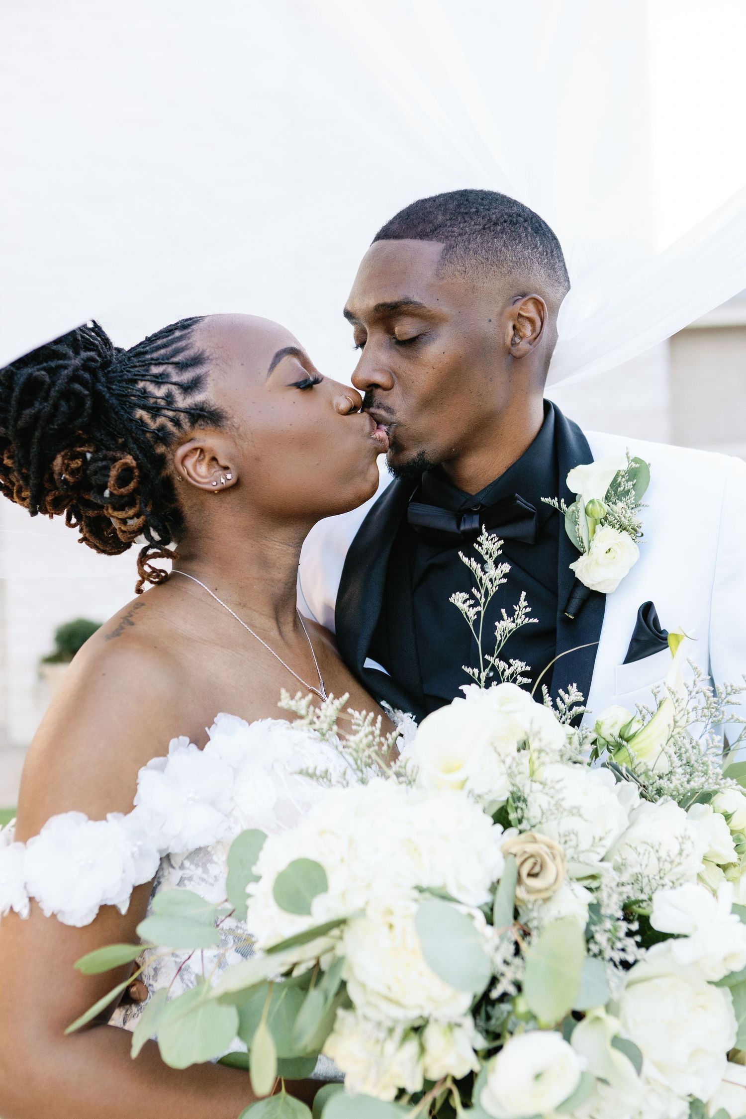 A romantic bride and groom share an intimate kiss during their outdoor wedding celebration.