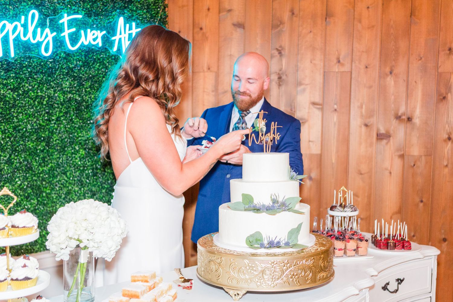 Tiered white wedding cake displayed on rustic wooden table with decorative elements.