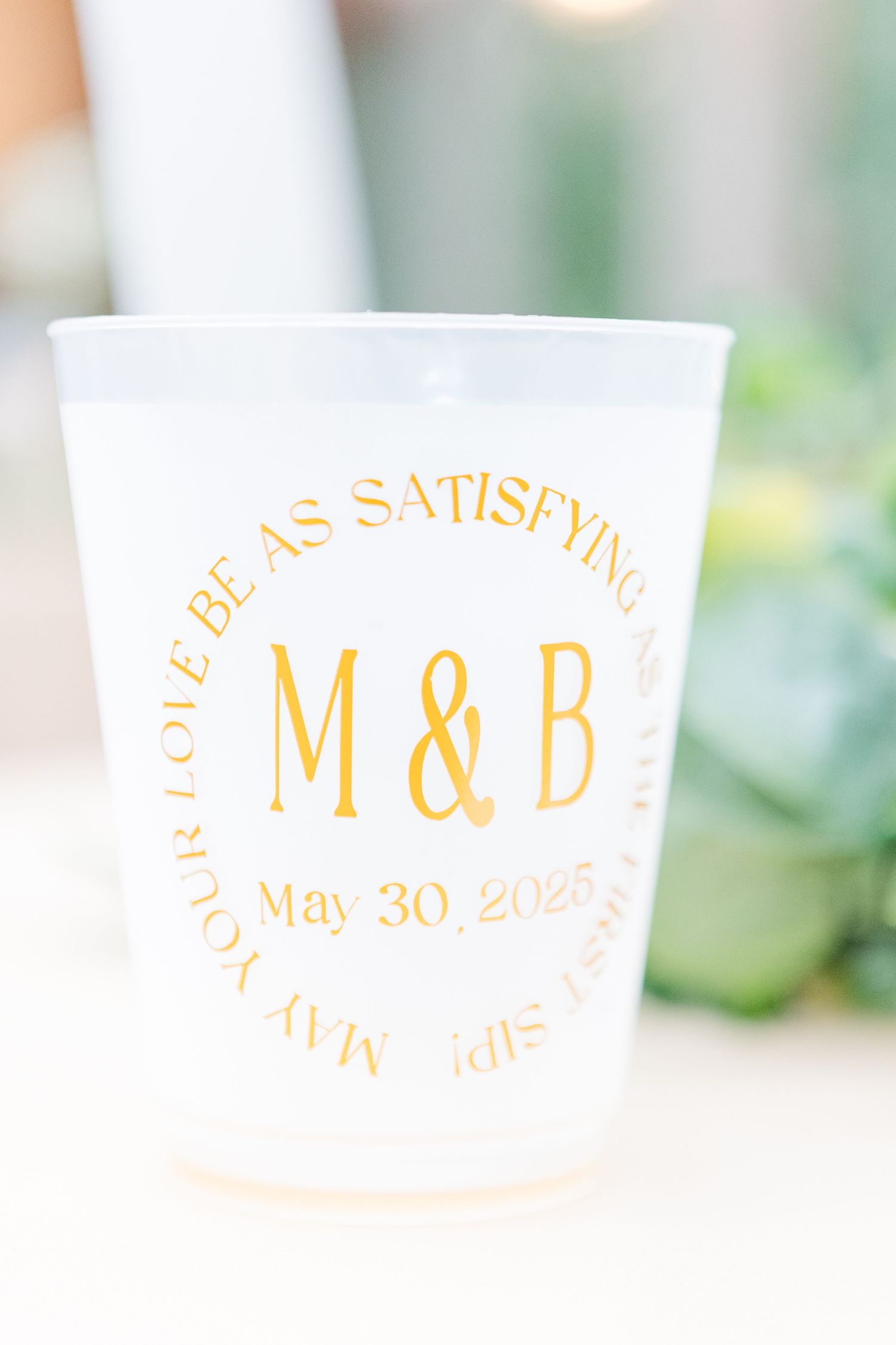 Wedding reception napkin with gold monogram M&D and date May 30 2023 printed in elegant lettering.