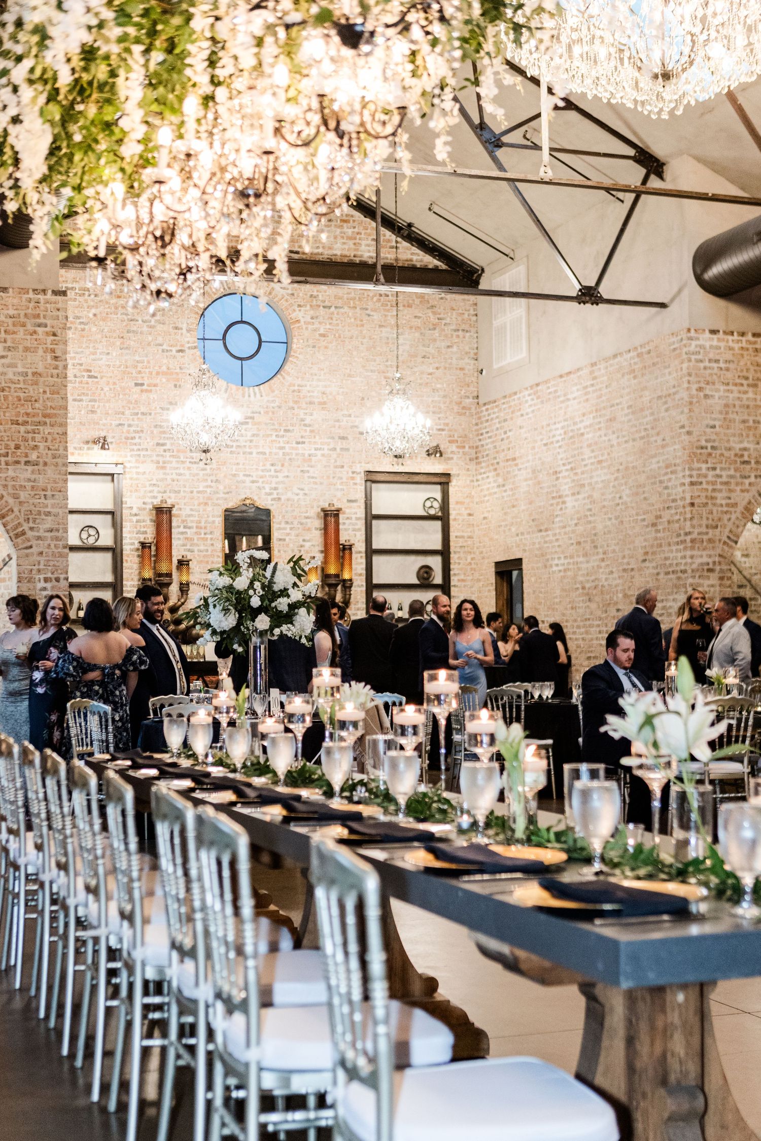 Modern industrial wedding venue with chandeliers, exposed brick walls and elegant table settings.