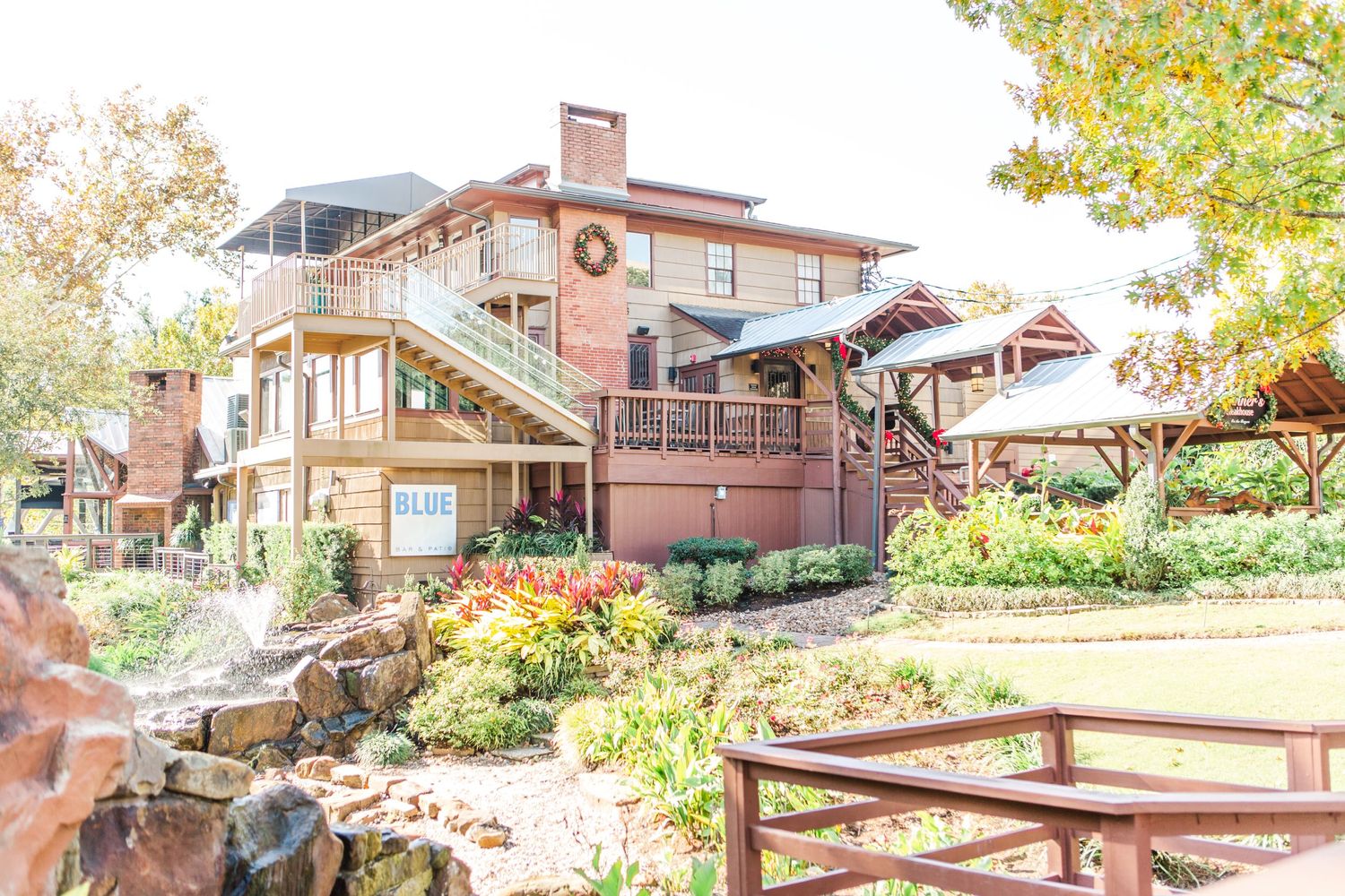 Exterior view of rustic wedding venue buildings with wooden deck and natural landscaping.