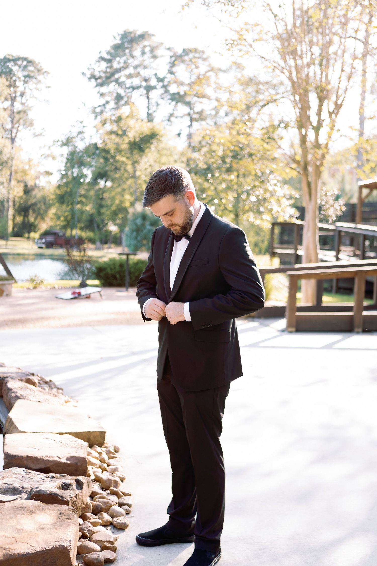 Wedding attire preparations showing formal black suit against outdoor backdrop.