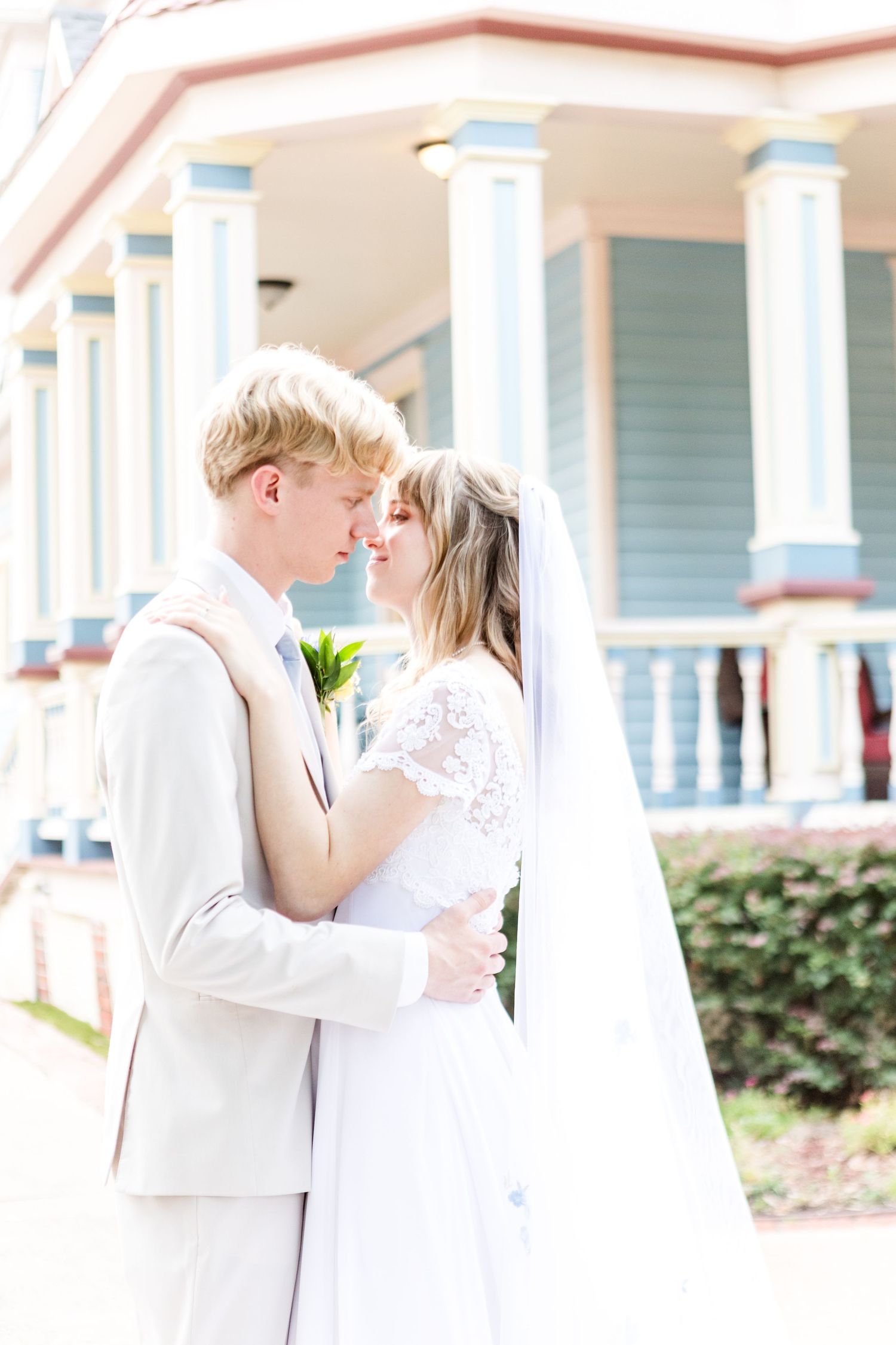Romantic wedding couple shares intimate first look moments on a white porch with columns.