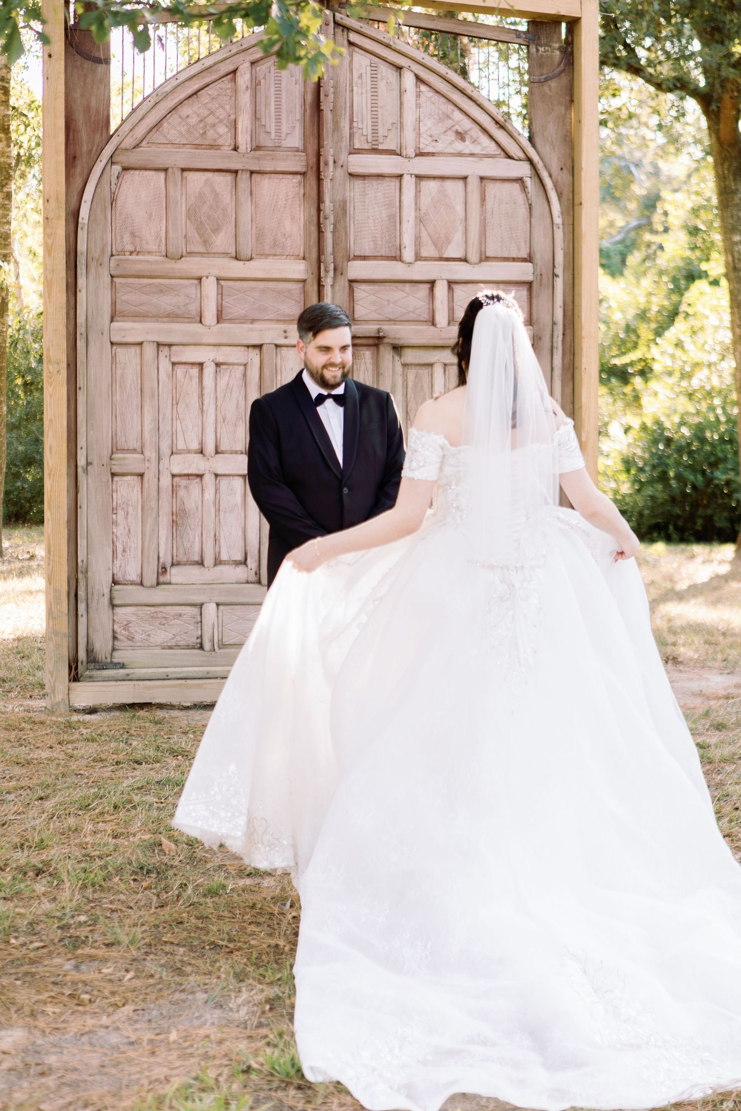 A bride and groom share a romantic moment in front of rustic wooden doors during an outdoor wedding photoshoot.