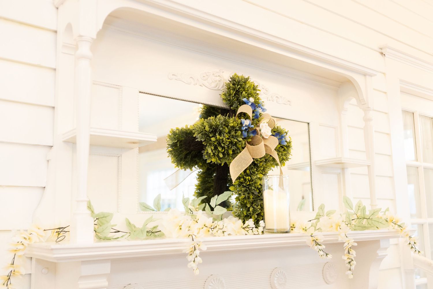 Elegant white wedding venue interior with decorative ceiling details and hanging greenery.