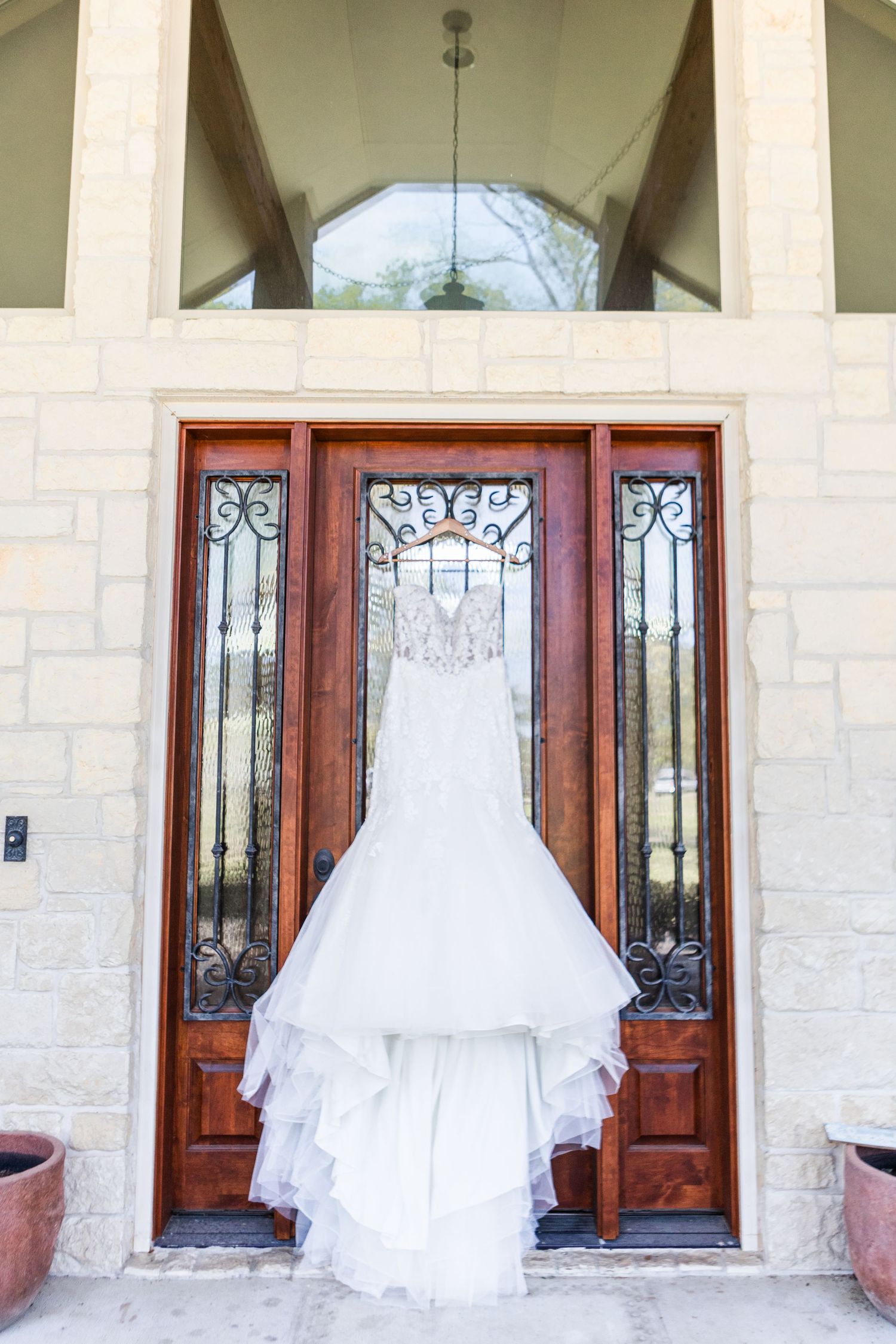 White wedding dress hanging on ornate wooden and glass front door.