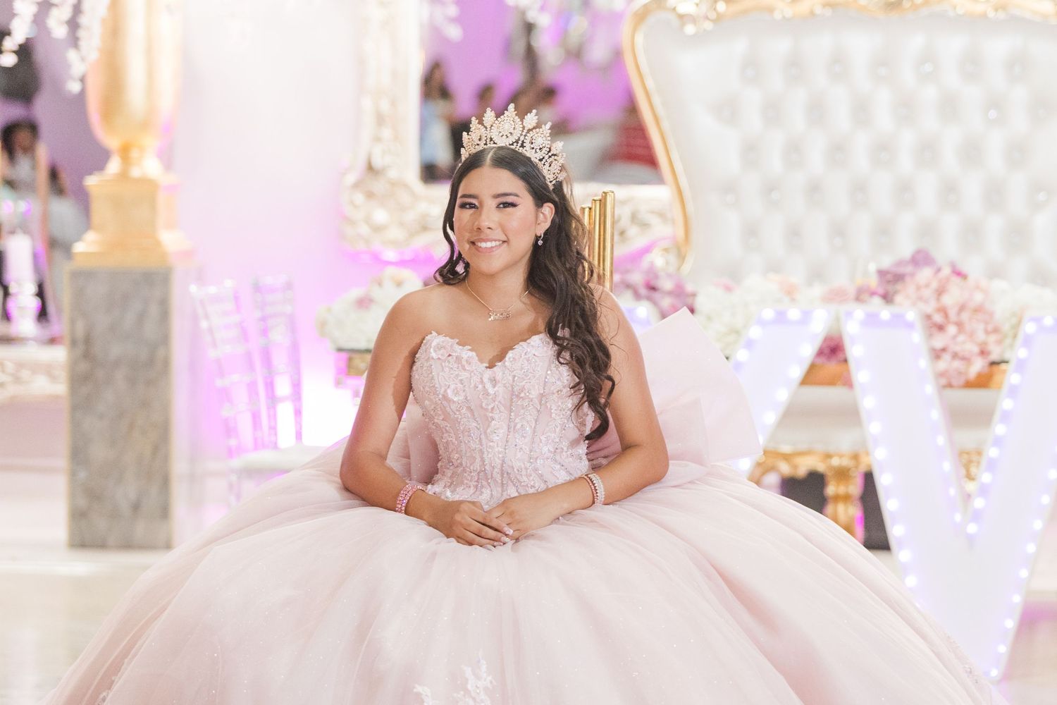 Elegant quinceanera celebration setup with pink and white throne chair against sparkly backdrop.