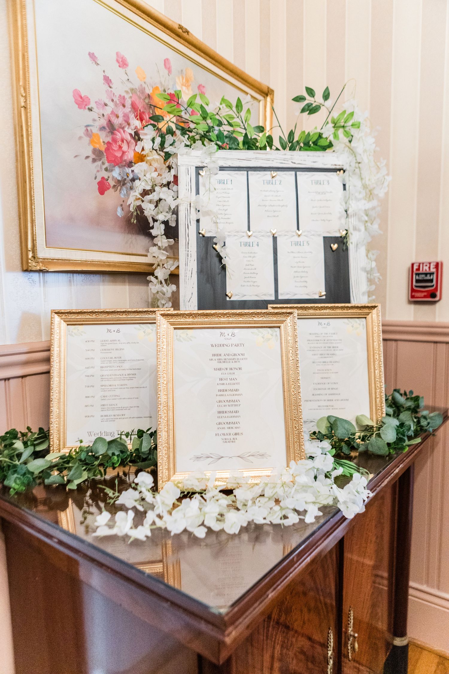 Wedding menu displays decorated with white flowers in gold frames.