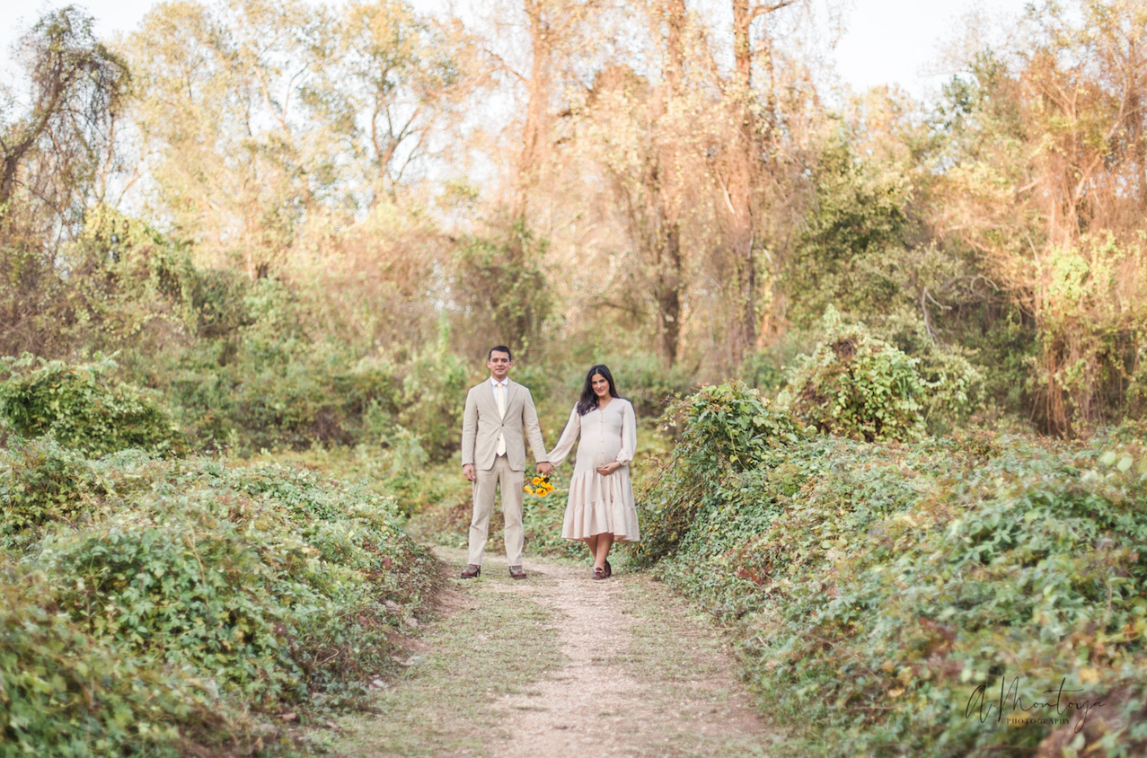 Couple walks hand in hand down tree-lined path during autumn photo session.