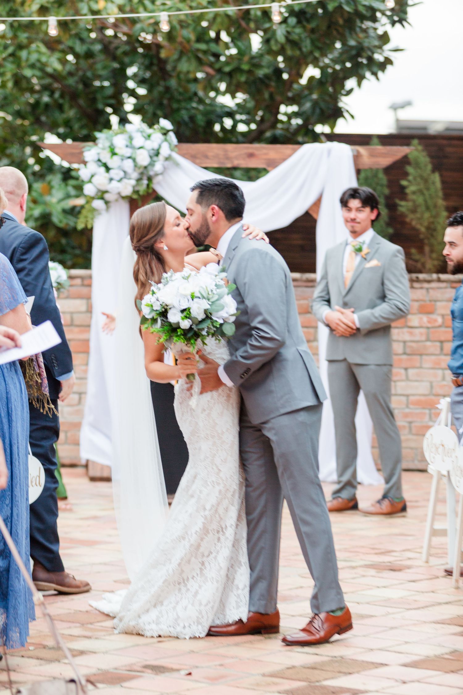 Wedding celebration unfolds against a backdrop of brick walls and white draped decorations.
