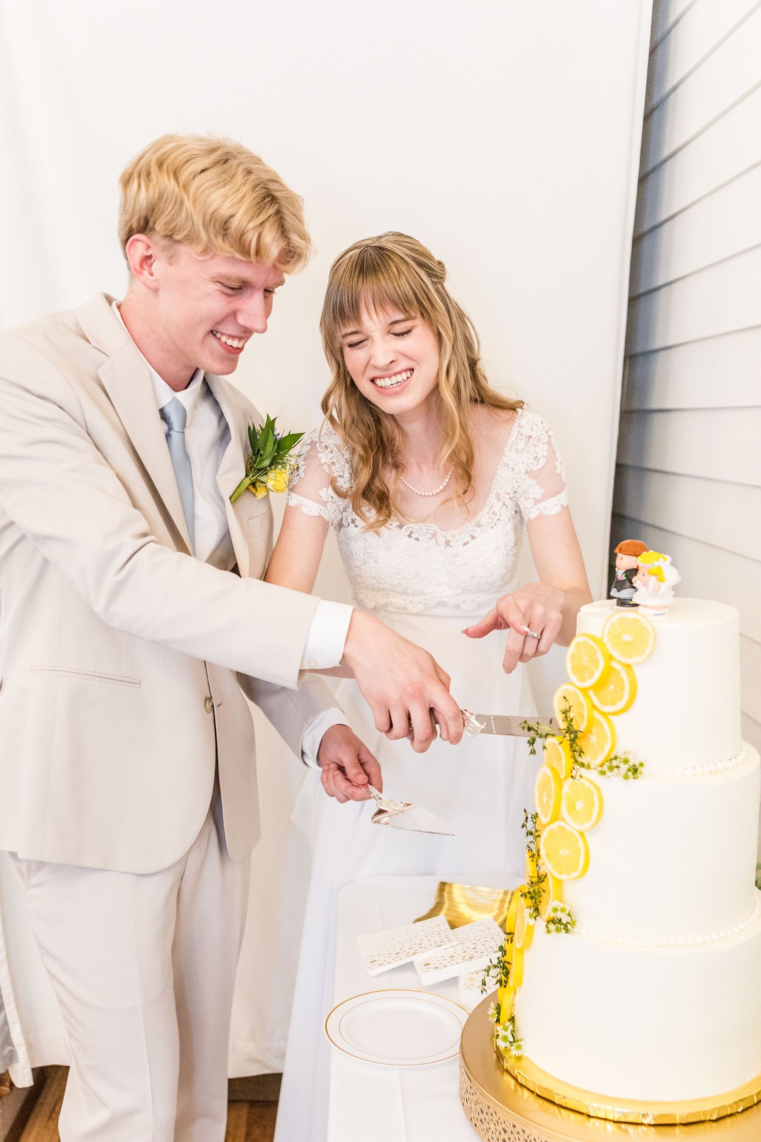 Newlyweds cutting their white wedding cake decorated with citrus slices.
