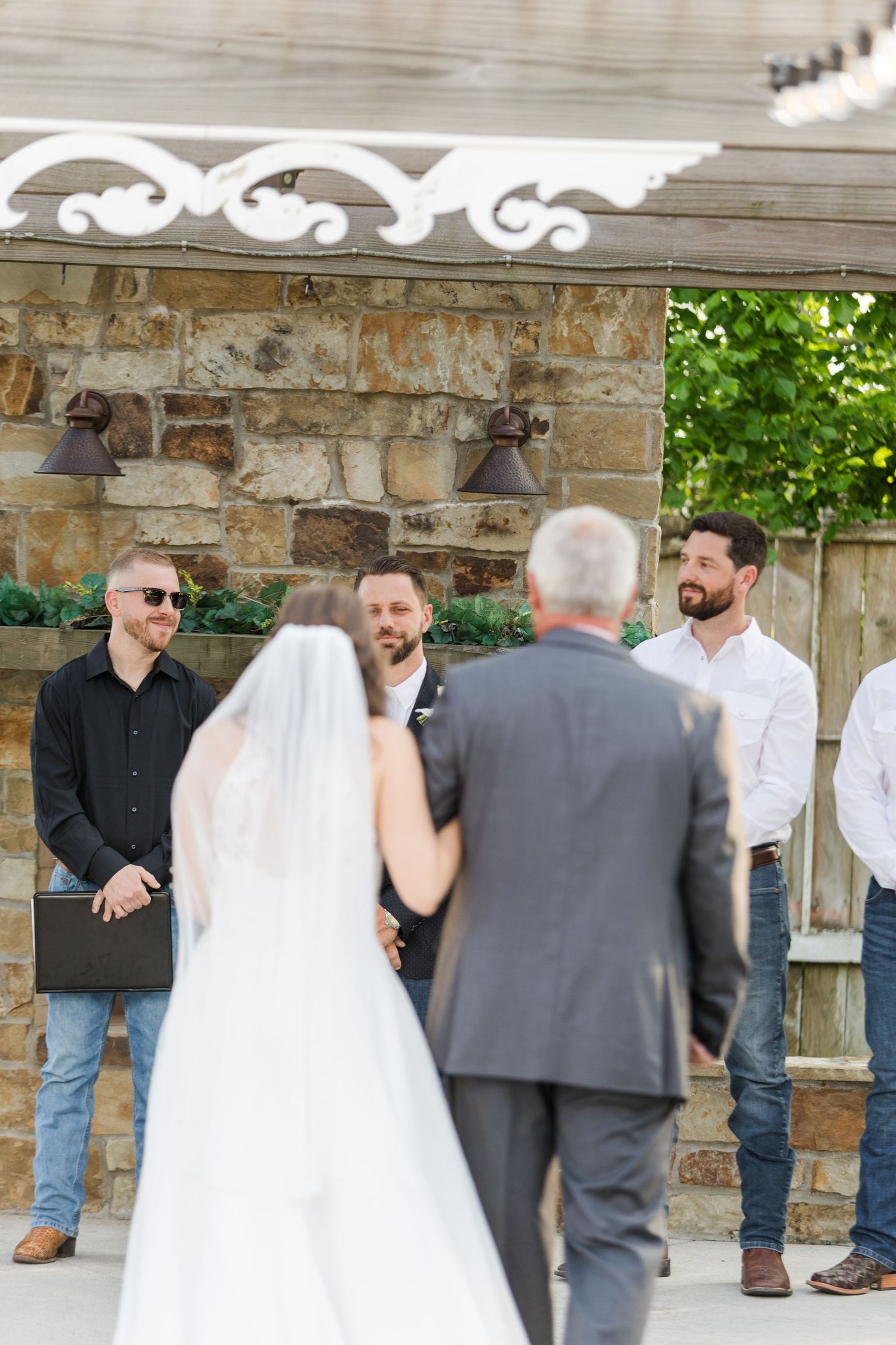 Wedding ceremony moments captured under stone pavilion with rustic details.
