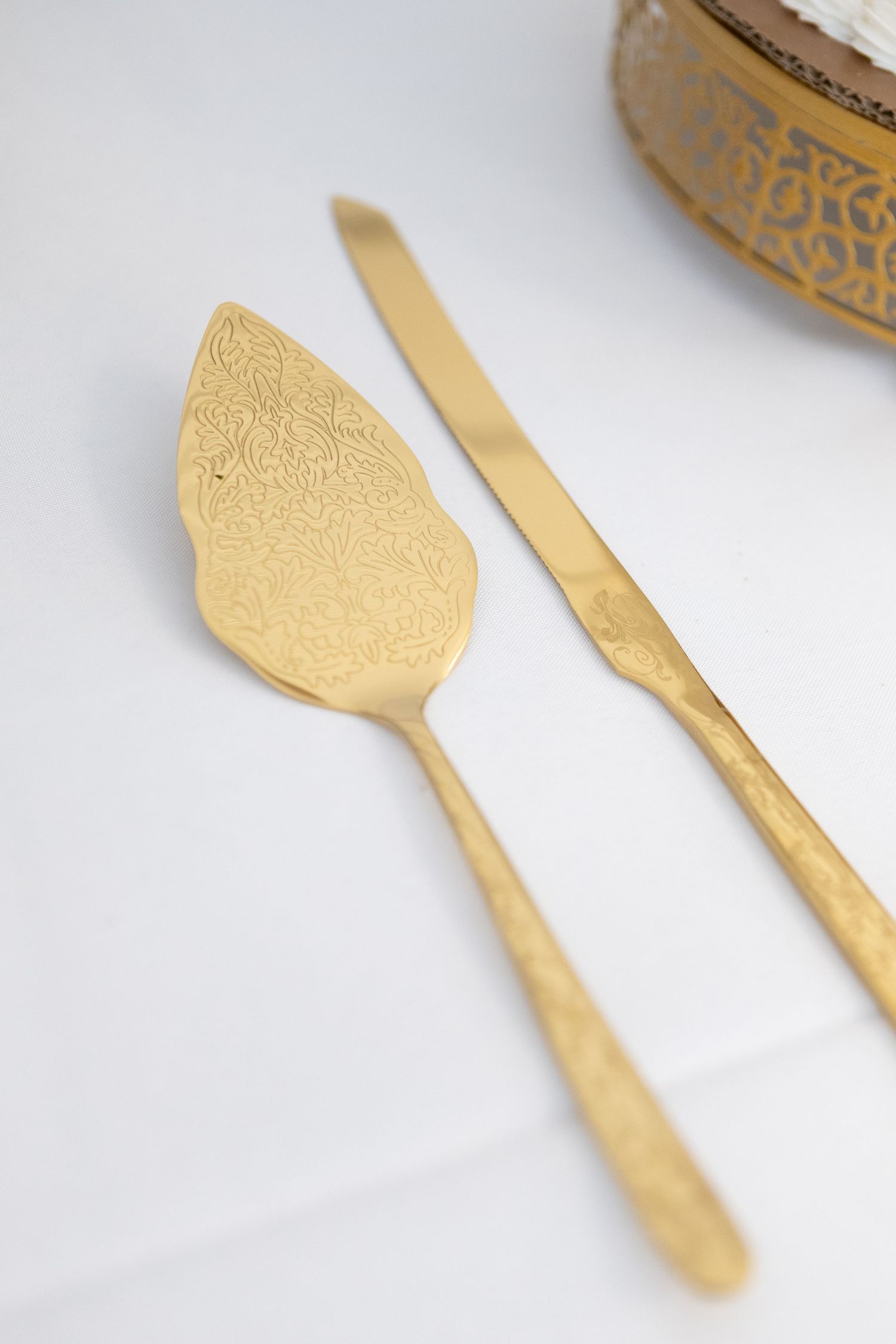 Gold decorative cake serving utensils with intricate pattern details.