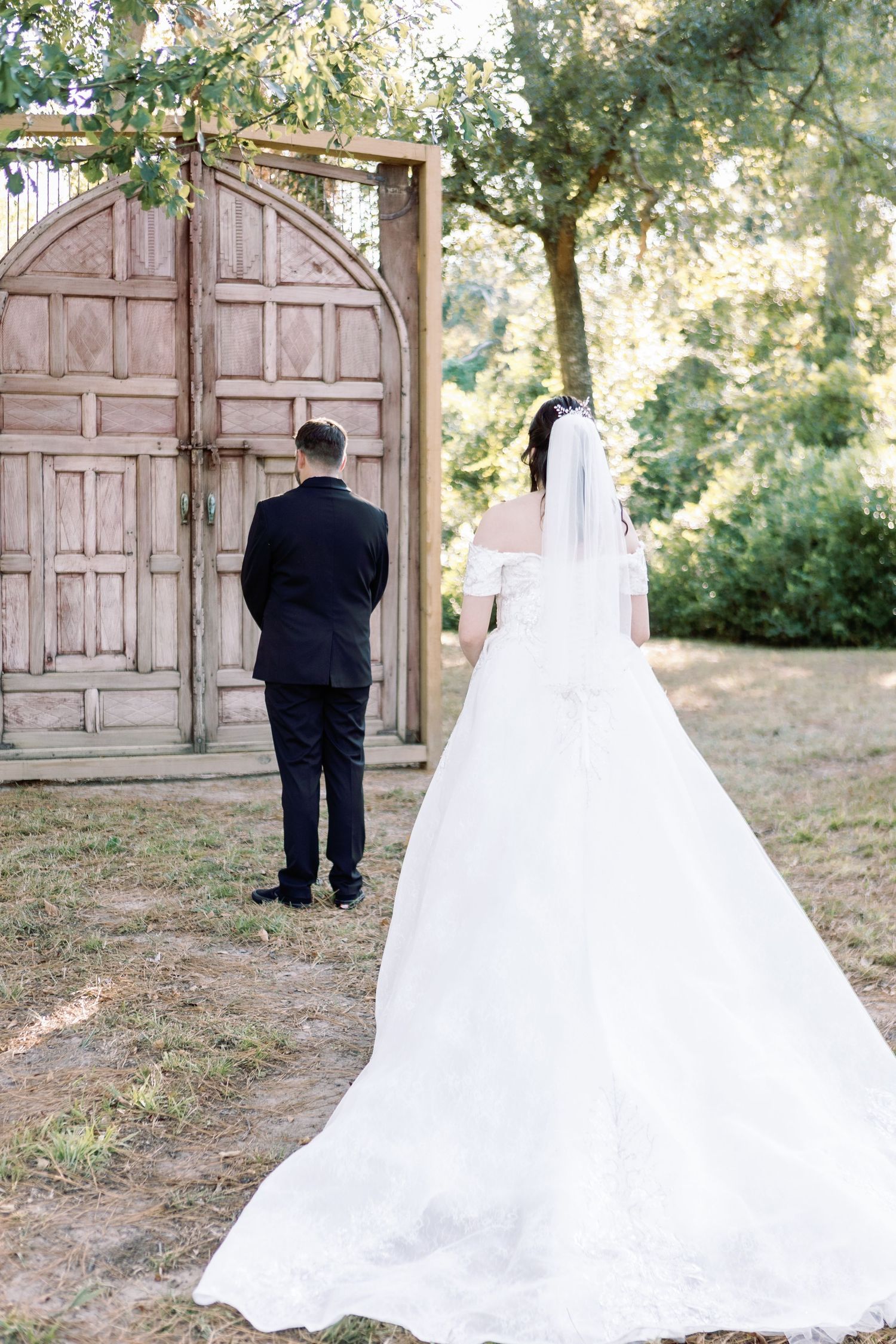 A wedding first look sequence showing a bride and groom meeting in front of vintage pink doors outdoors.