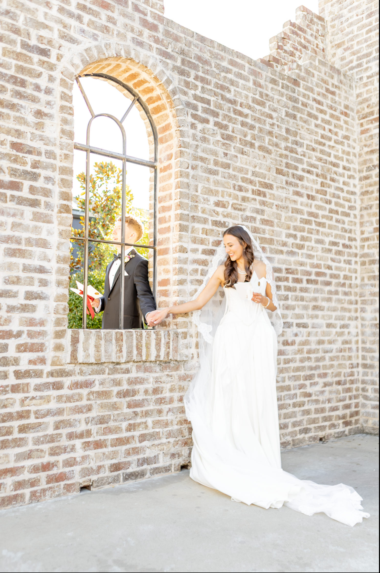 Bride poses in front of rustic brick wall with arched windows in a creative wedding photo sequence.