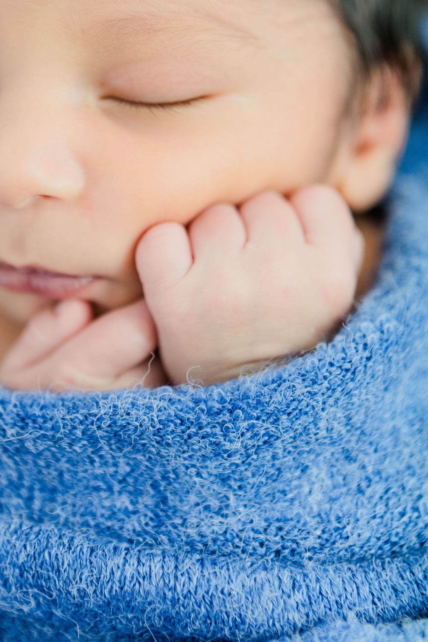 Close-up detail of someone resting on a bright blue textured blanket.