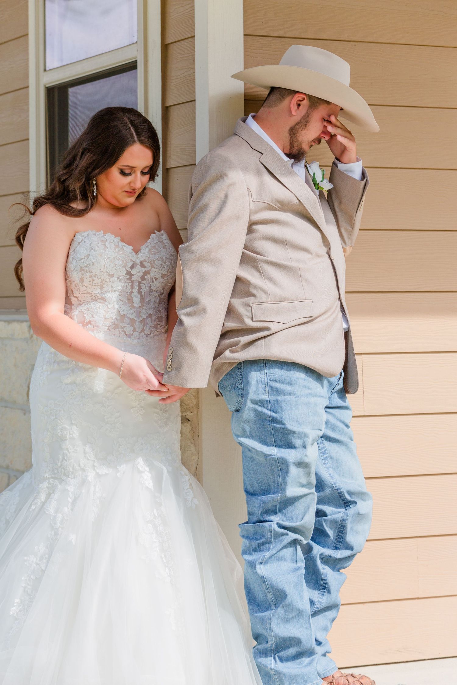 A bride in a white ballgown poses for first look photos on a porch.