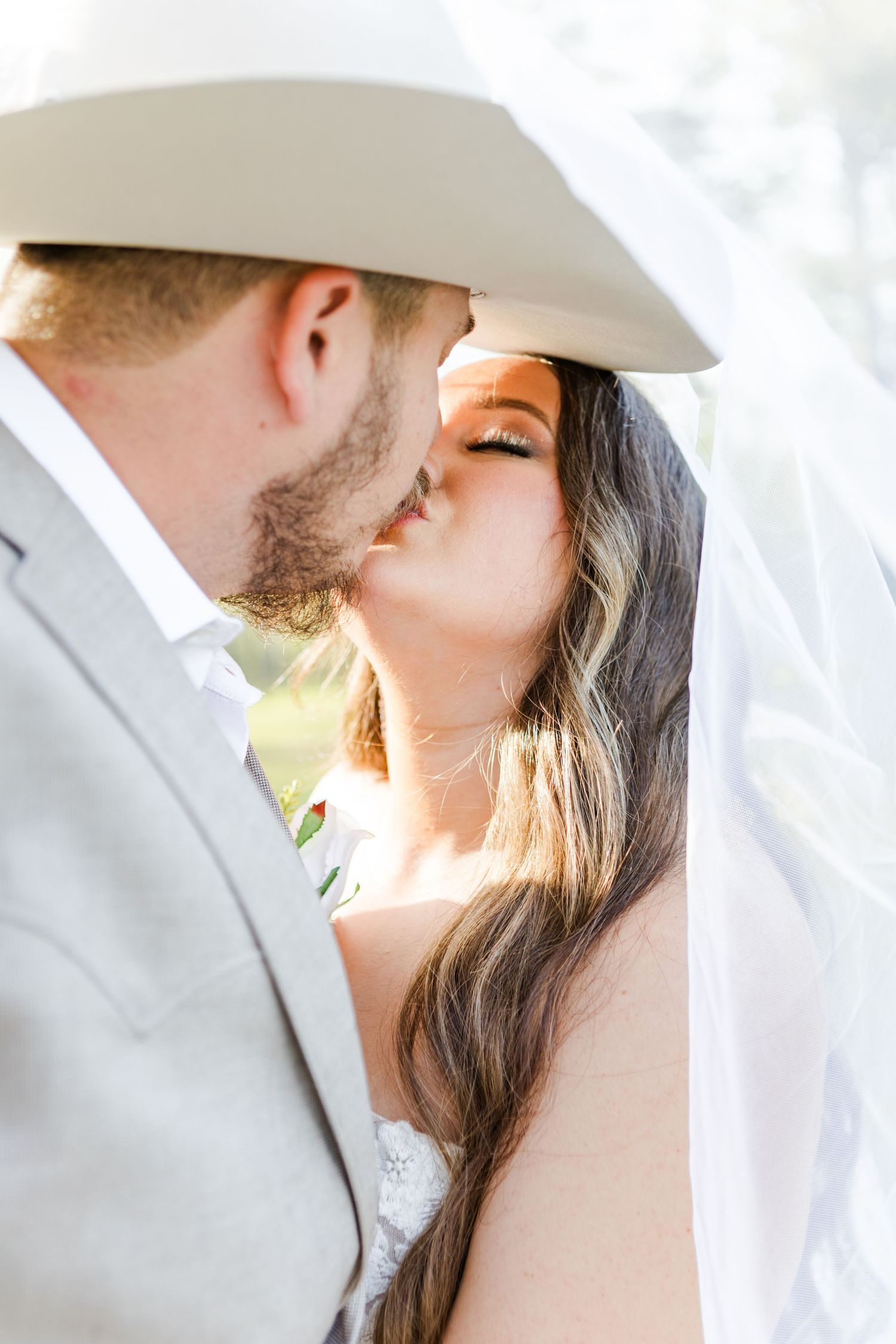 Close-up romantic portrait featuring a white cowboy hat and gentle lighting.