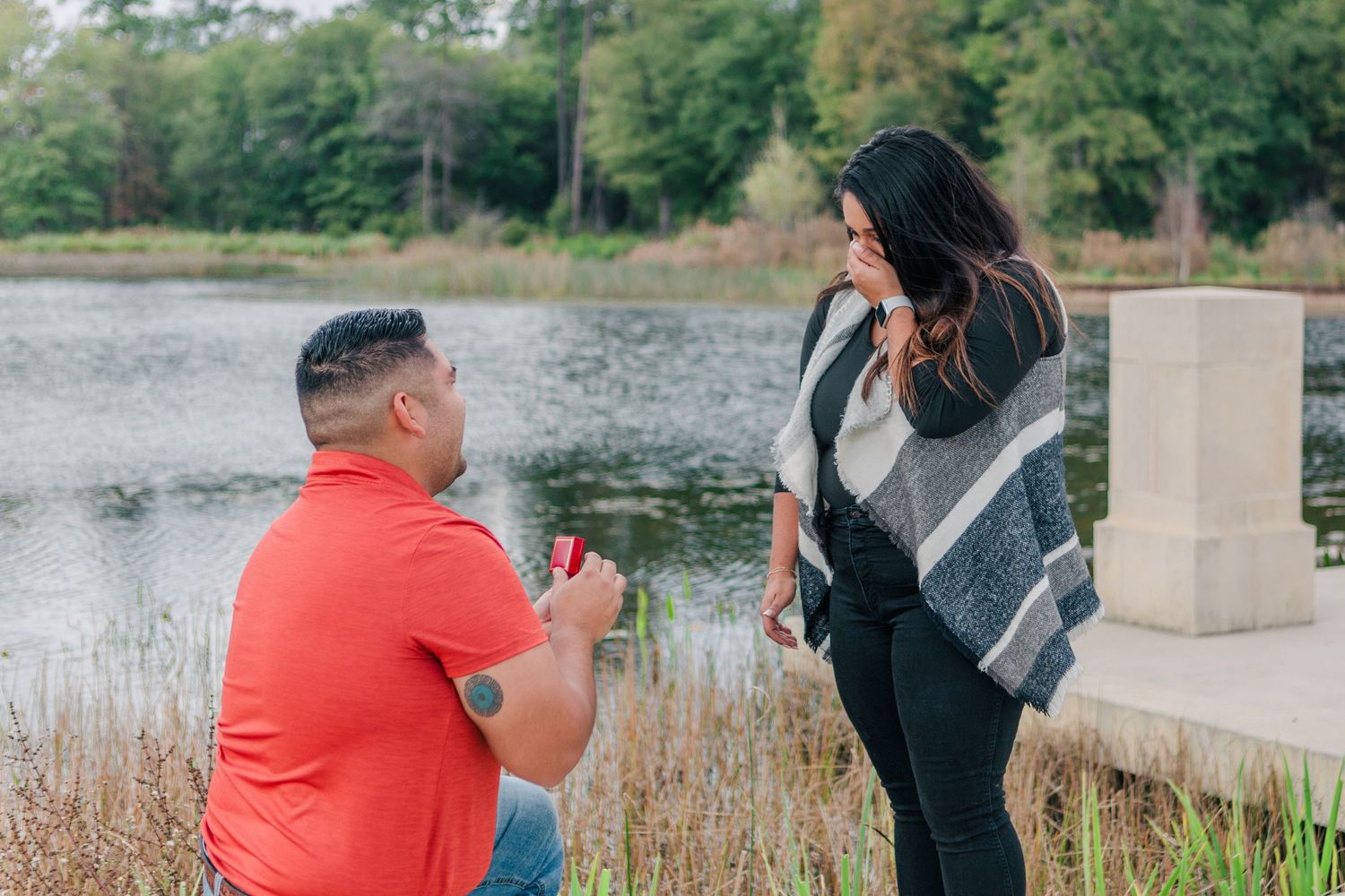 A surprise proposal moment captured by a lake with natural scenery.
