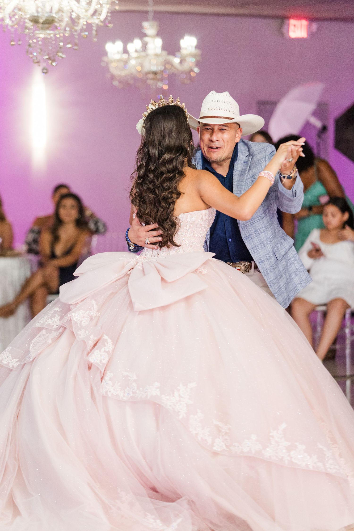 Traditional dance moment at a quinceañera celebration with a guest in cowboy attire and a flowing pink ballgown.