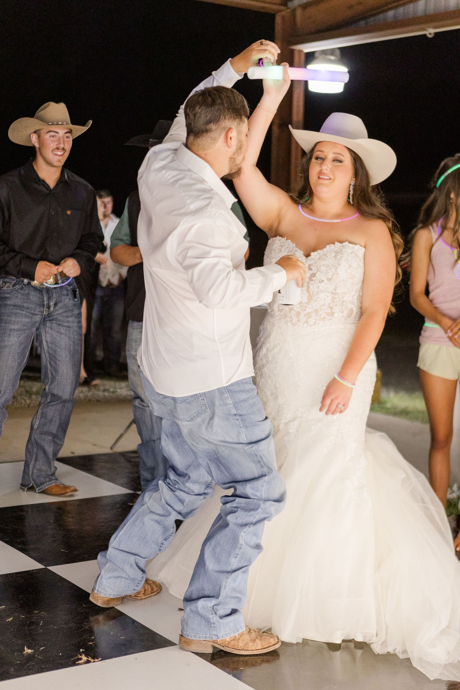 A couple dances together at a wedding reception on a black and white checkered dance floor.