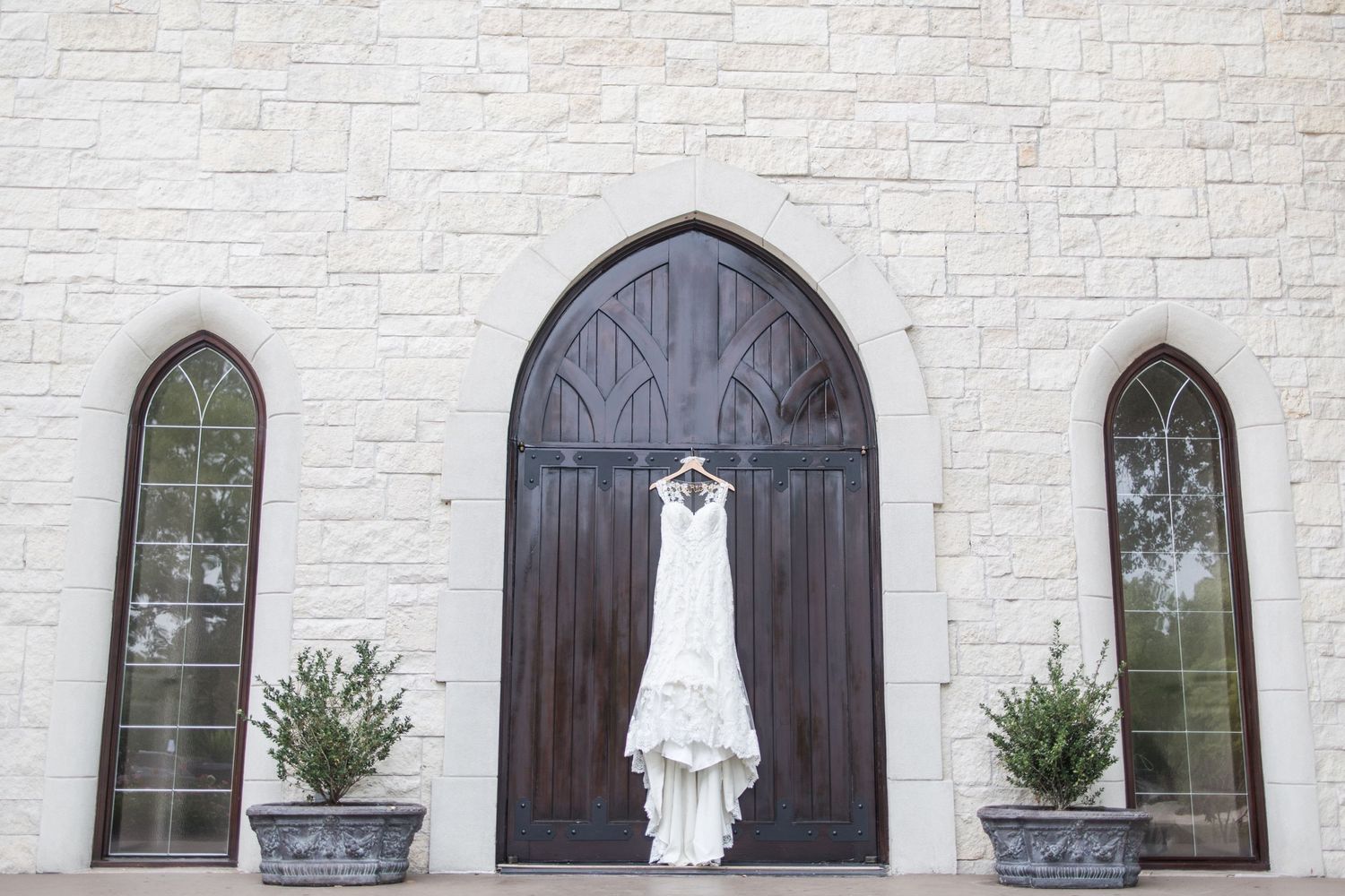 White stone chapel exterior with gothic arched windows and wooden doors.
