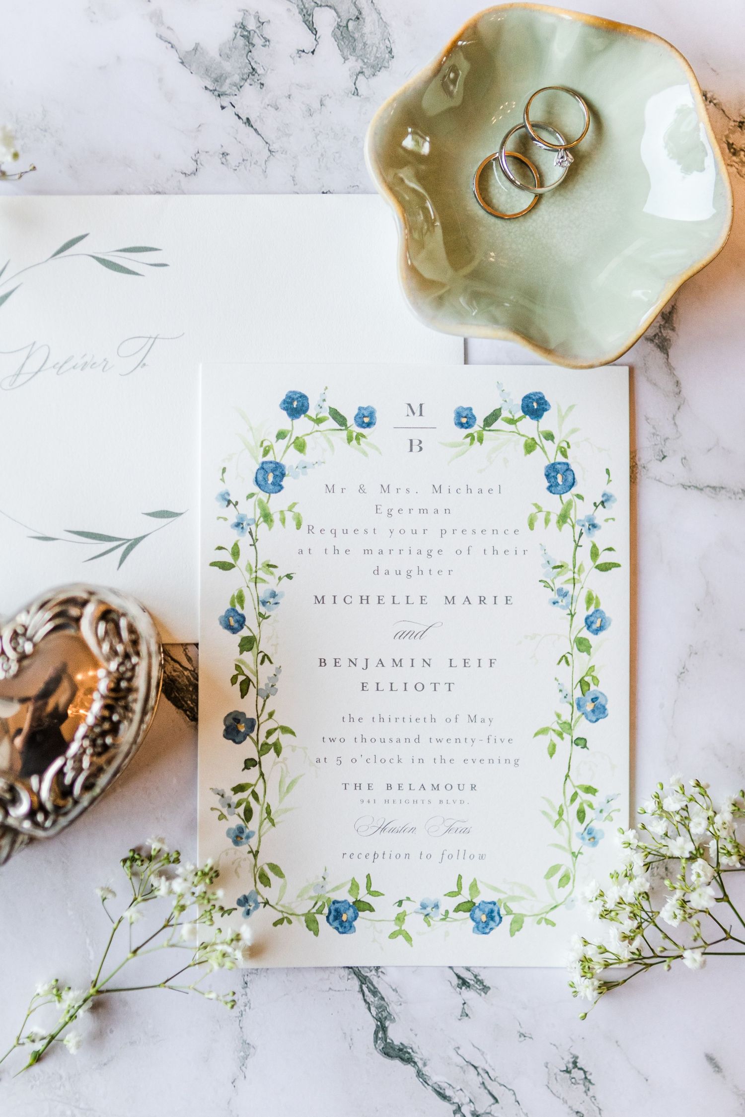 Wedding invitation suite with delicate blue floral design on marble background.