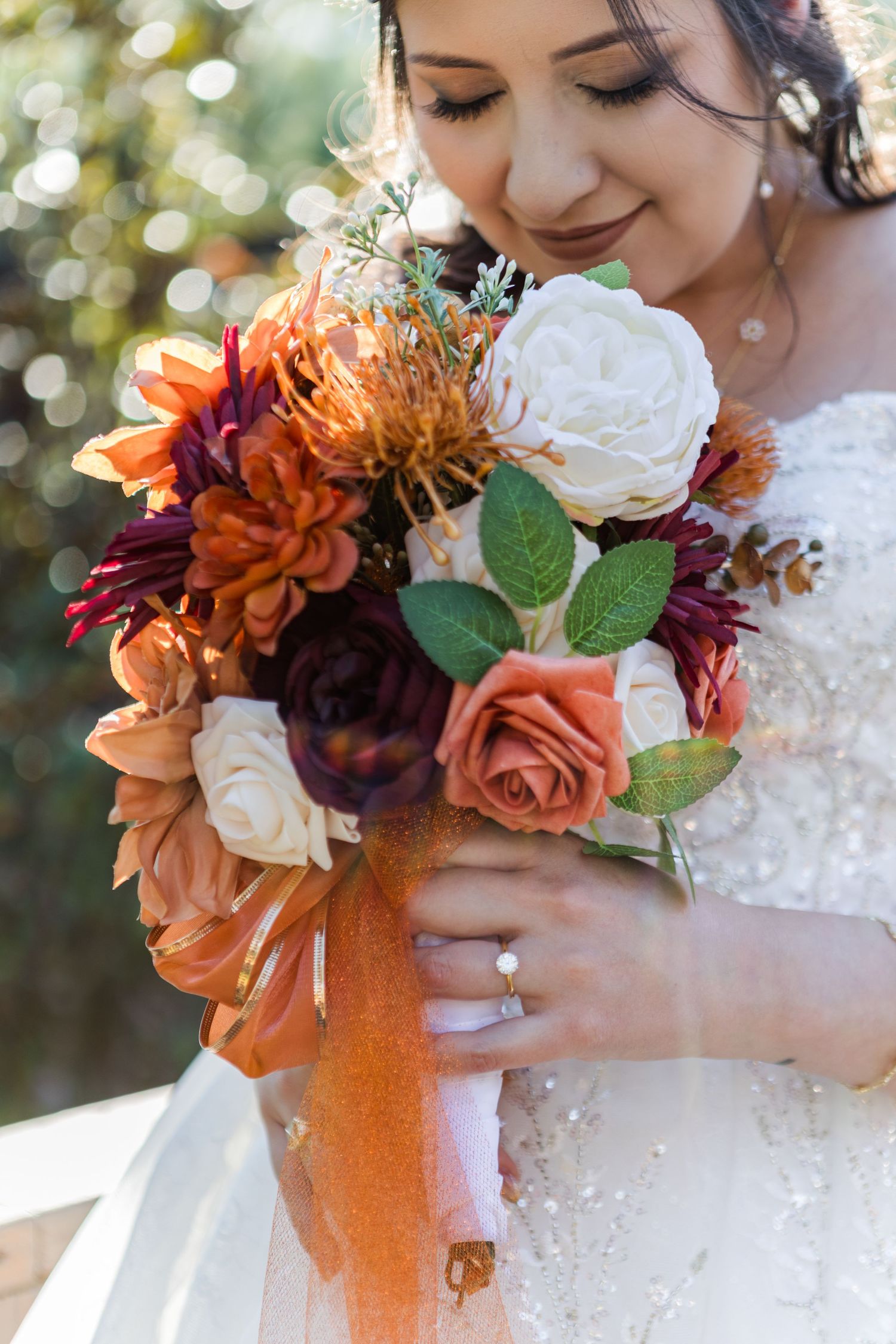 Beautiful autumn-themed bridal bouquet featuring orange, burgundy and white flowers with lush greenery.