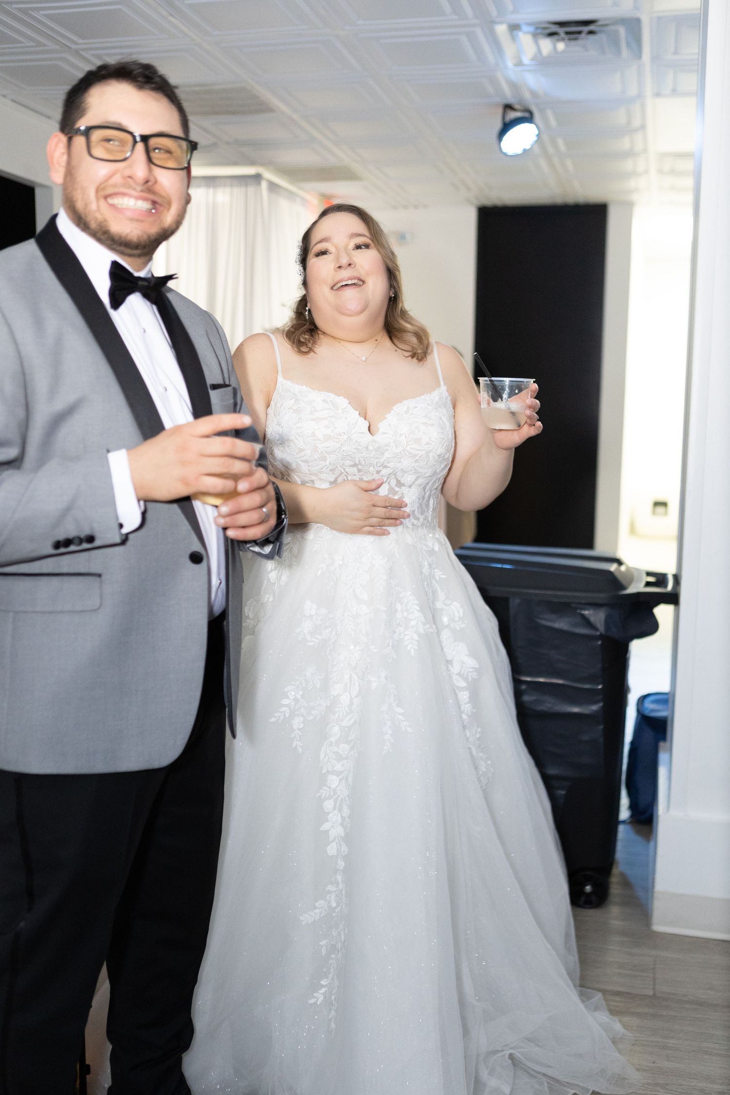 Formal event attendees in elegant attire sharing drinks and laughter.