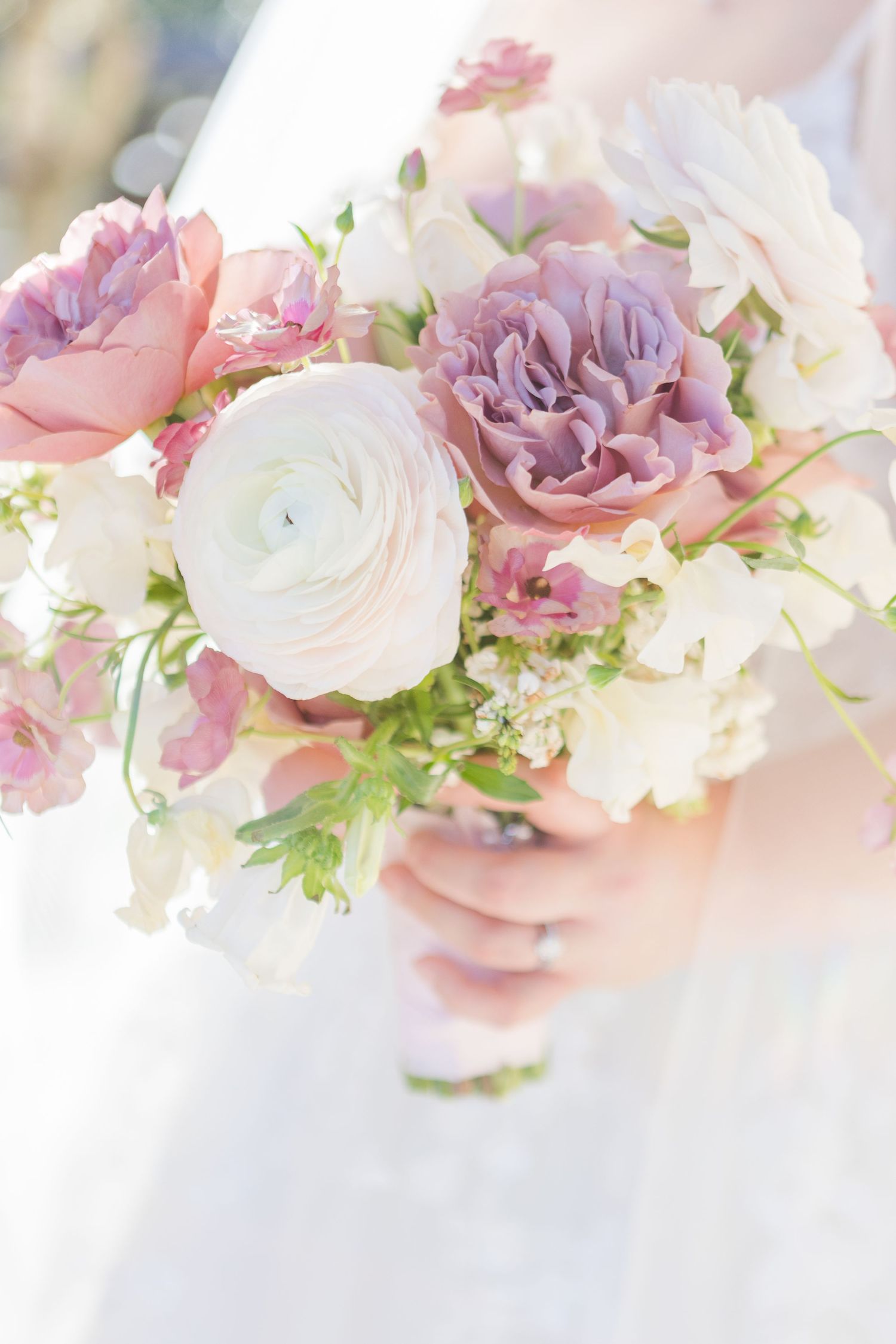 Romantic bouquet featuring pink and lavender roses with white ranunculus flowers and greenery.