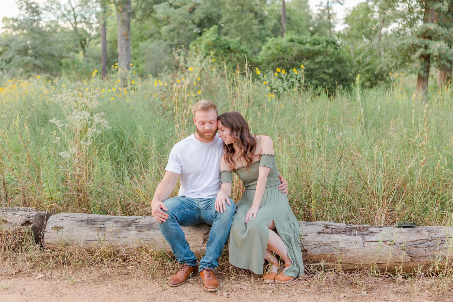 Couple sharing intimate moments during engagement photo session in a rustic outdoor setting.