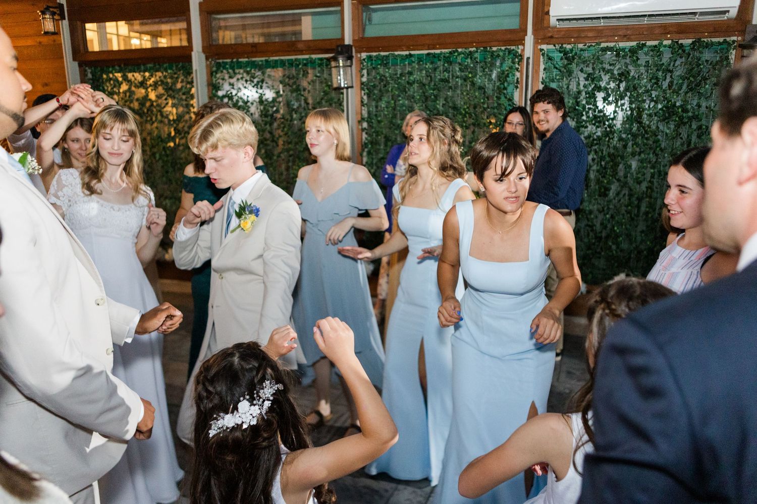 Wedding guests dancing and celebrating during a lively reception with blue bridesmaid dresses.