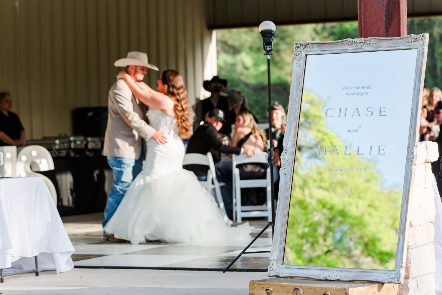 Elegant wedding reception setup with white chairs under a covered pavilion.