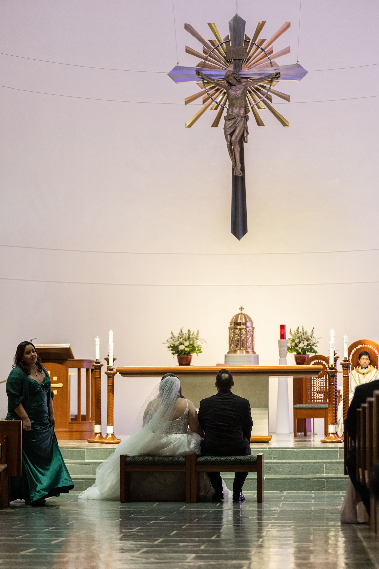 Modern church interior with decorative ceiling light and pews during a wedding ceremony.
