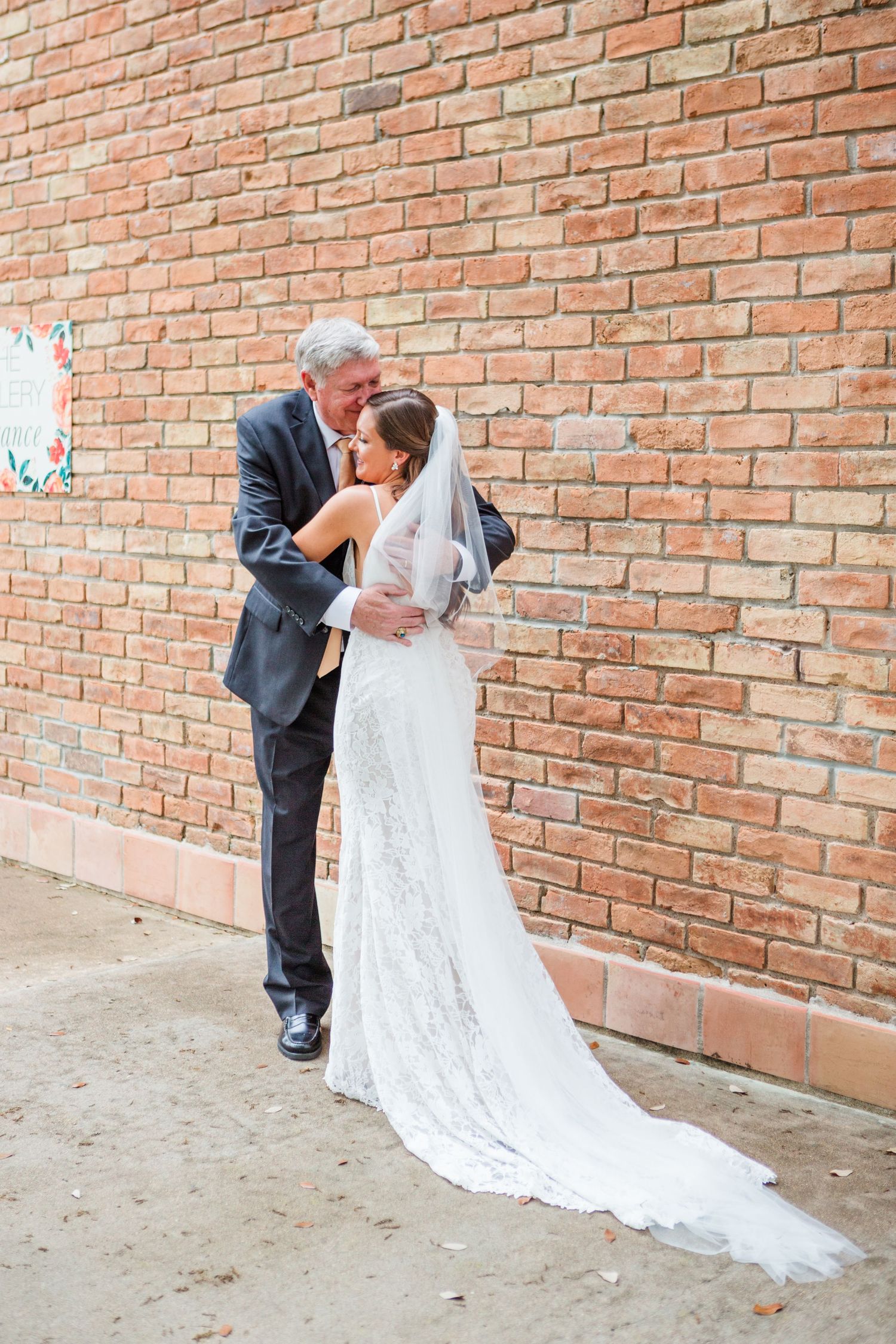 Sweet candid moments captured against rustic brick wall background.