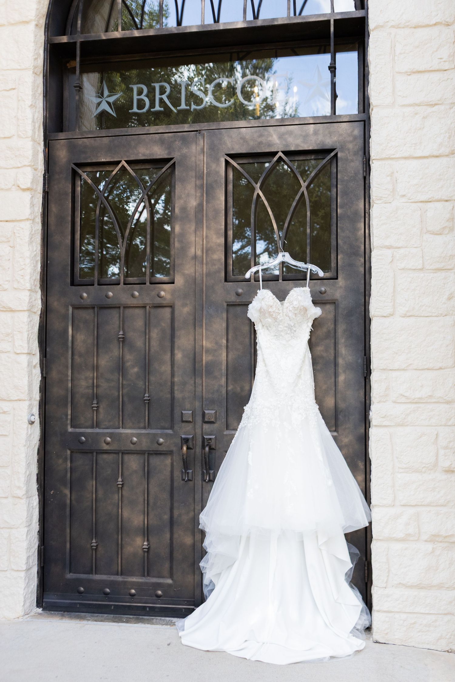 Multiple elegant white wedding dresses displayed in storefront windows at a bridal boutique.