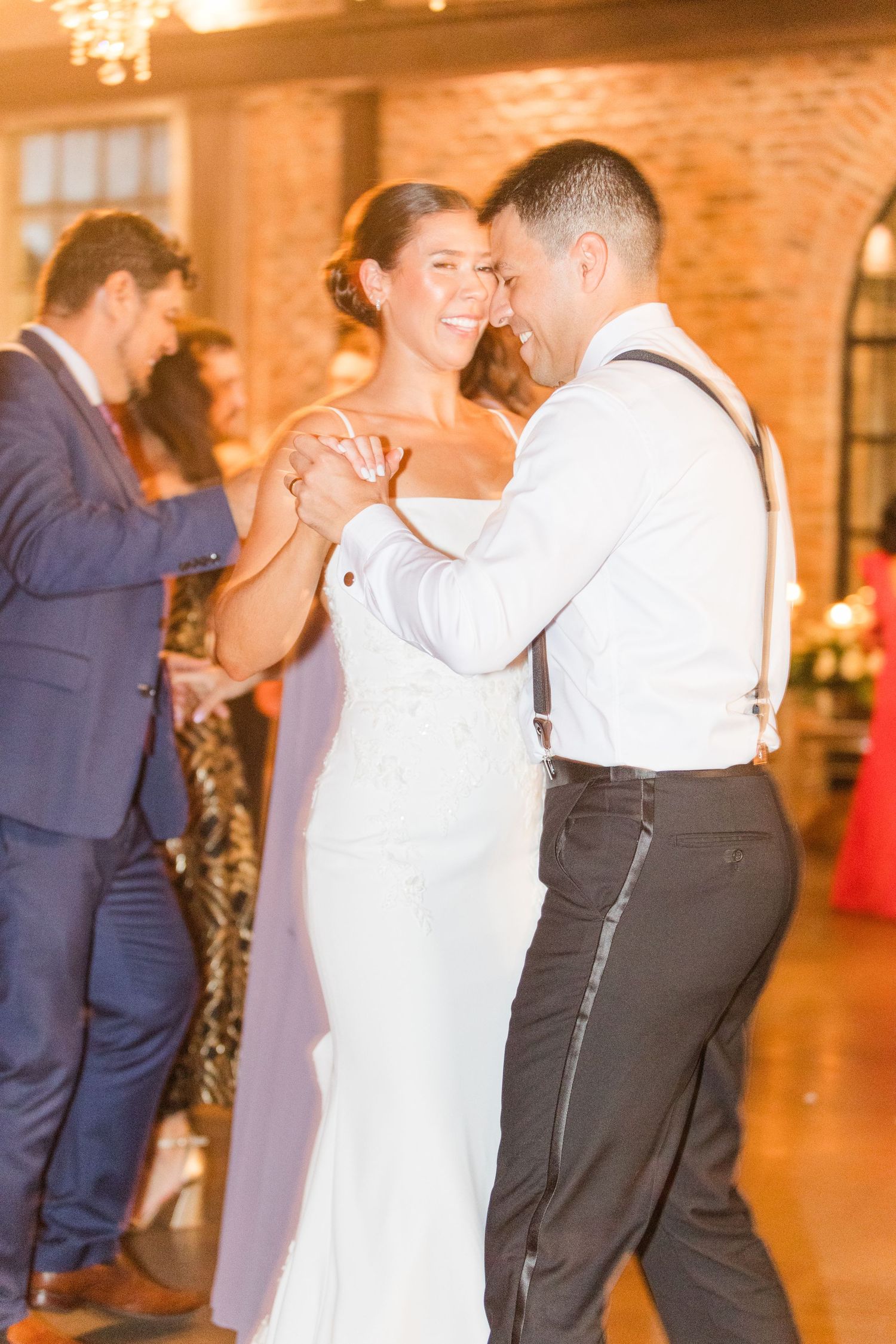 Couples dancing together on a warm-lit dance floor at an elegant indoor venue.