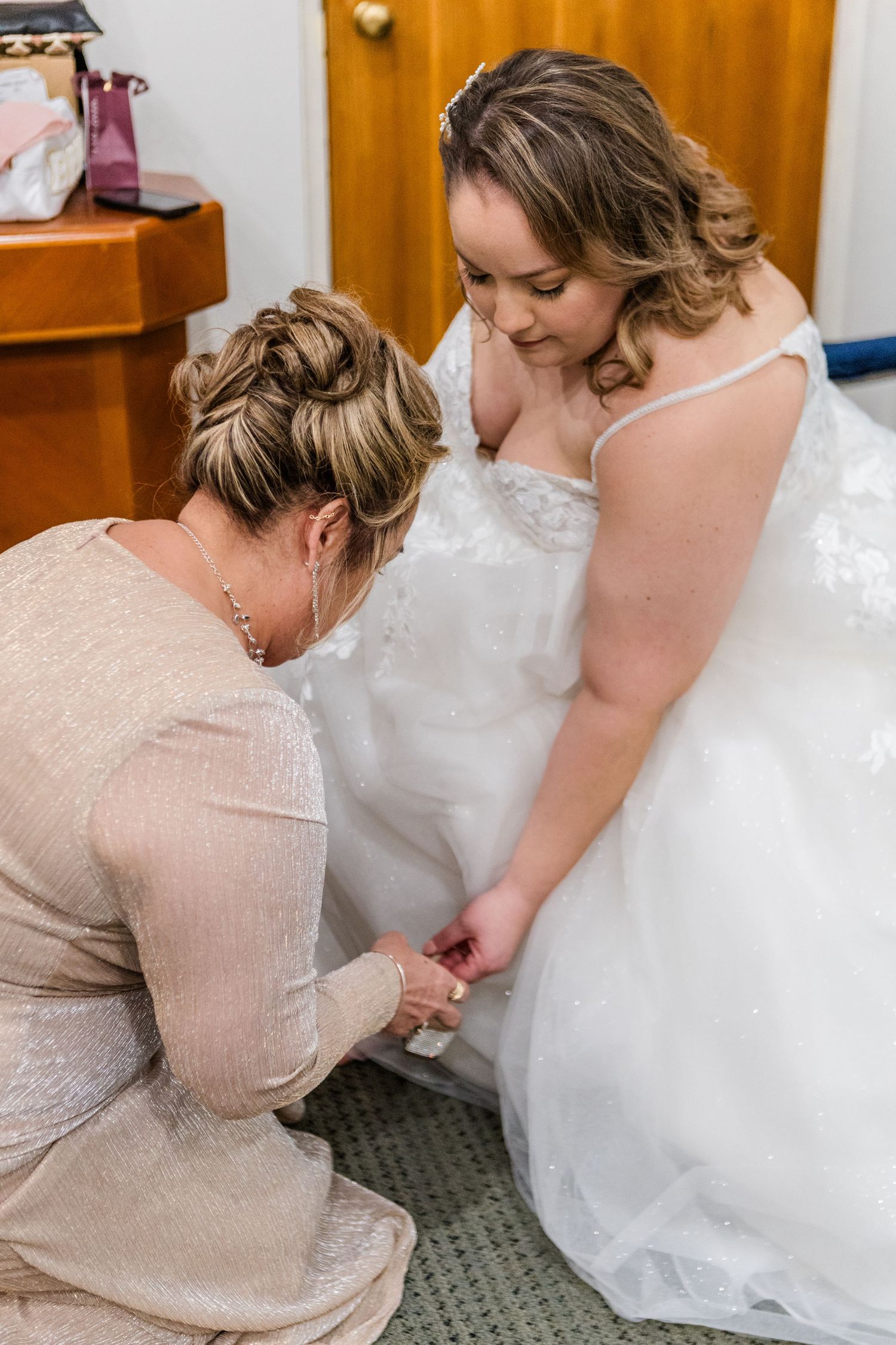 Wedding dress detail showing someone helping with the gown's adjustments.