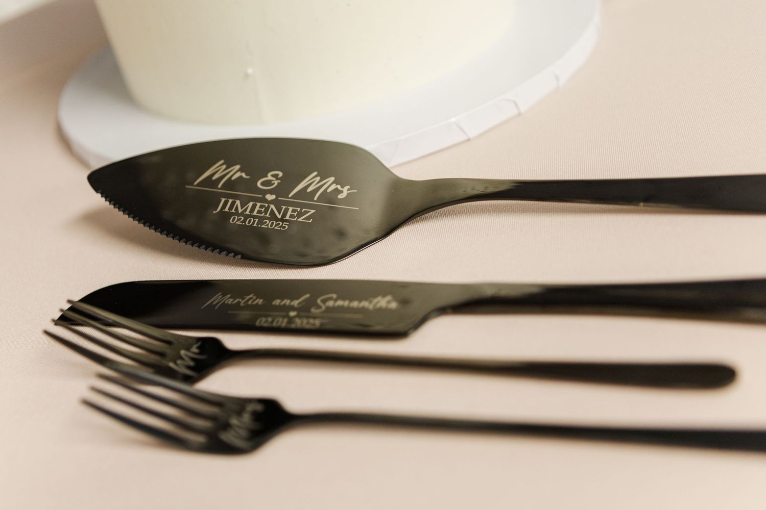 Elegant black and gold wedding utensils with personalized engraving displayed at a reception.