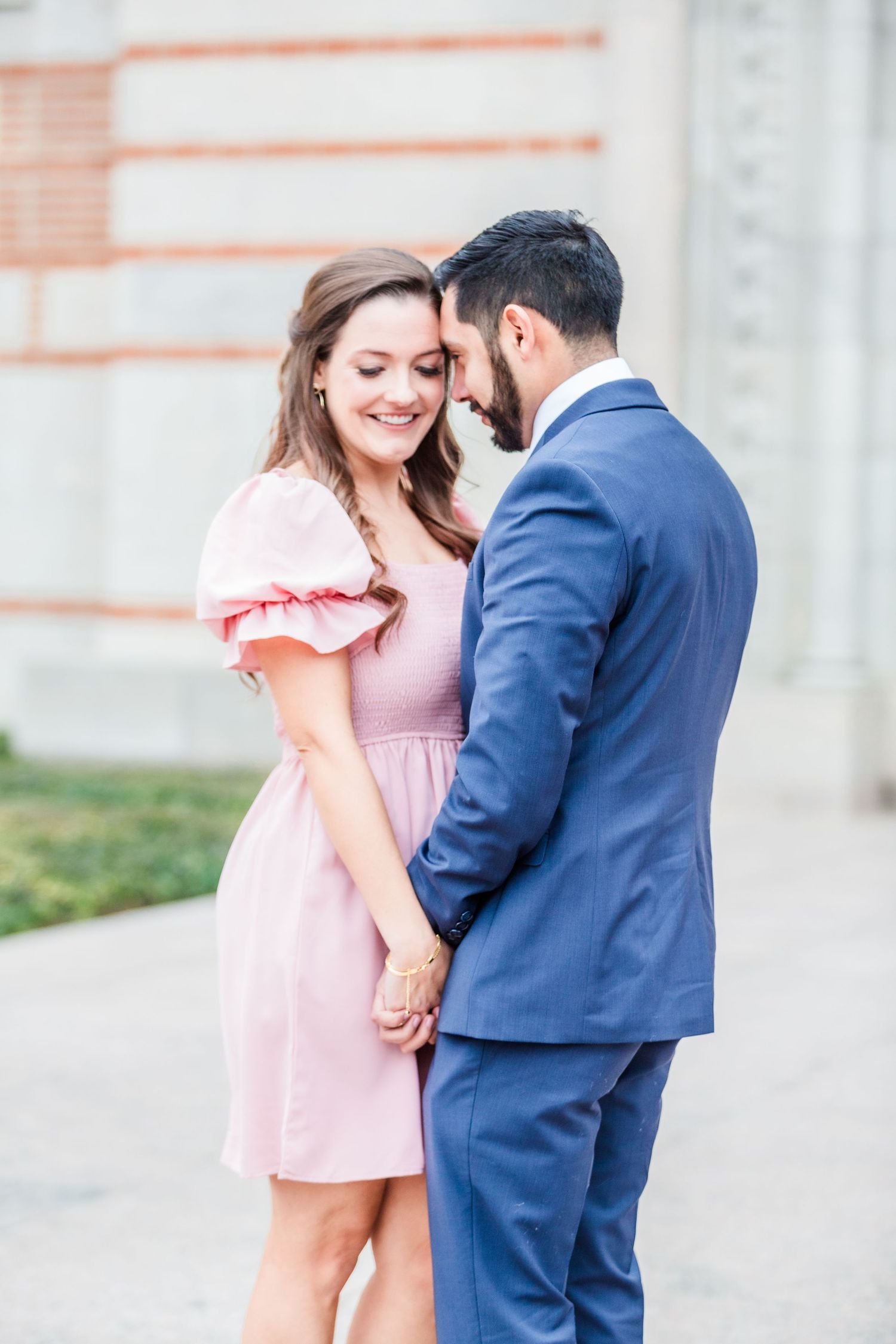 A couple shares an intimate moment in front of classic architecture.
