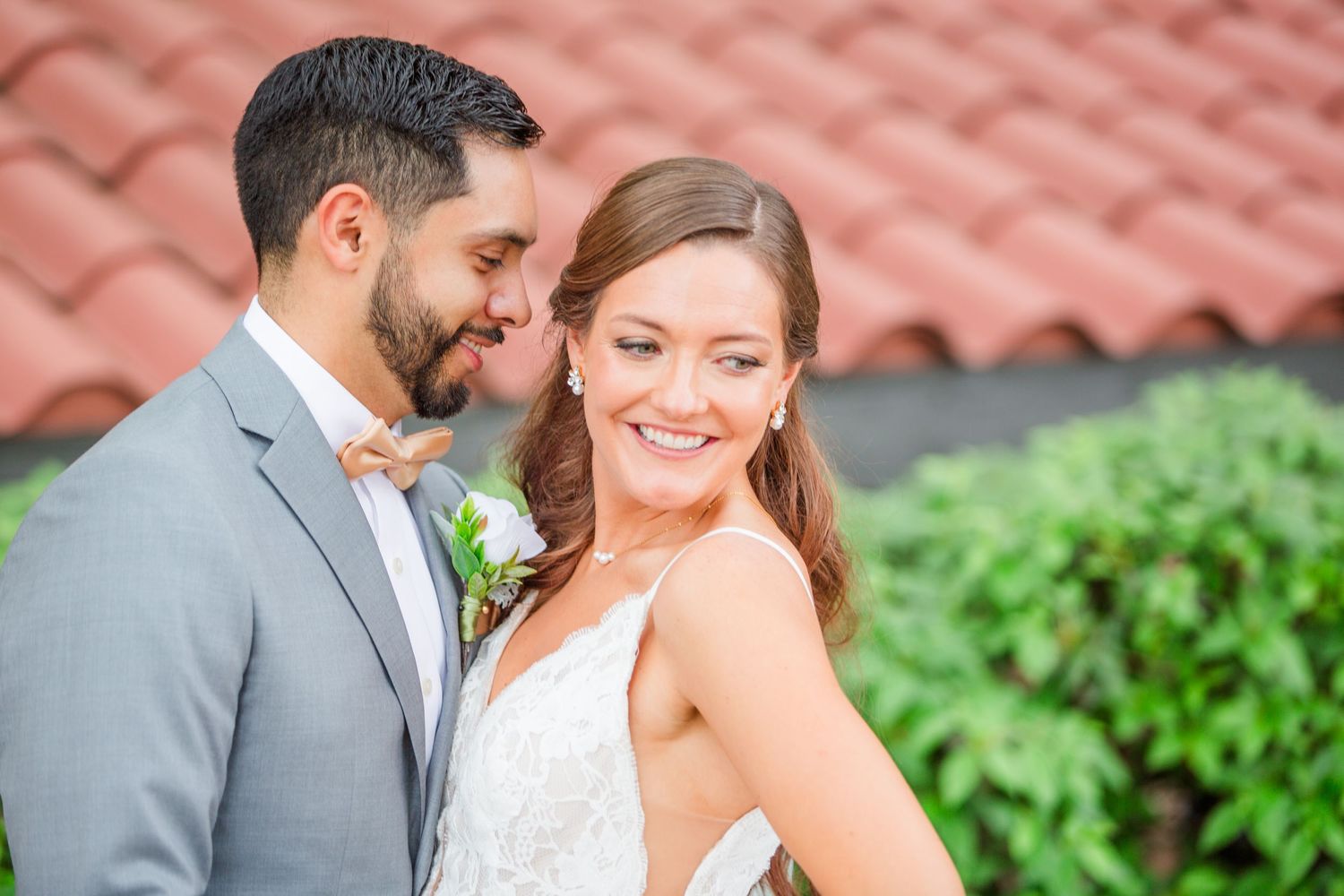 Sun-lit wedding portrait with terra cotta roof tiles in background.
